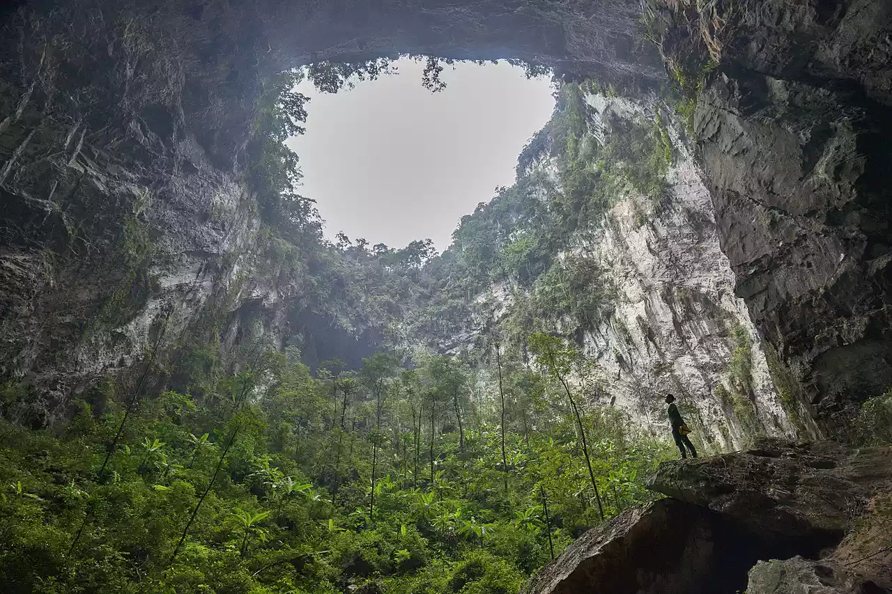 Person standing under an opening of the Son Doong Cave