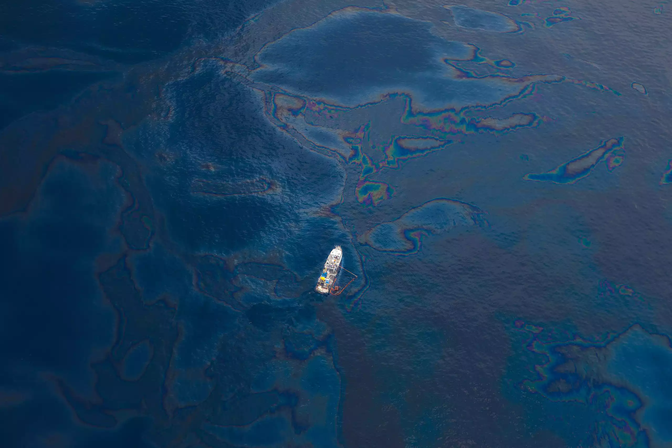 Aerial view of a lone boat in the Gulf of Mexico with oil visible on water's surface