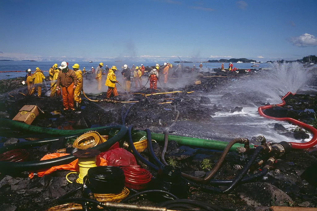 Firefighters spray water from firehoses to clean up oil from shorelines