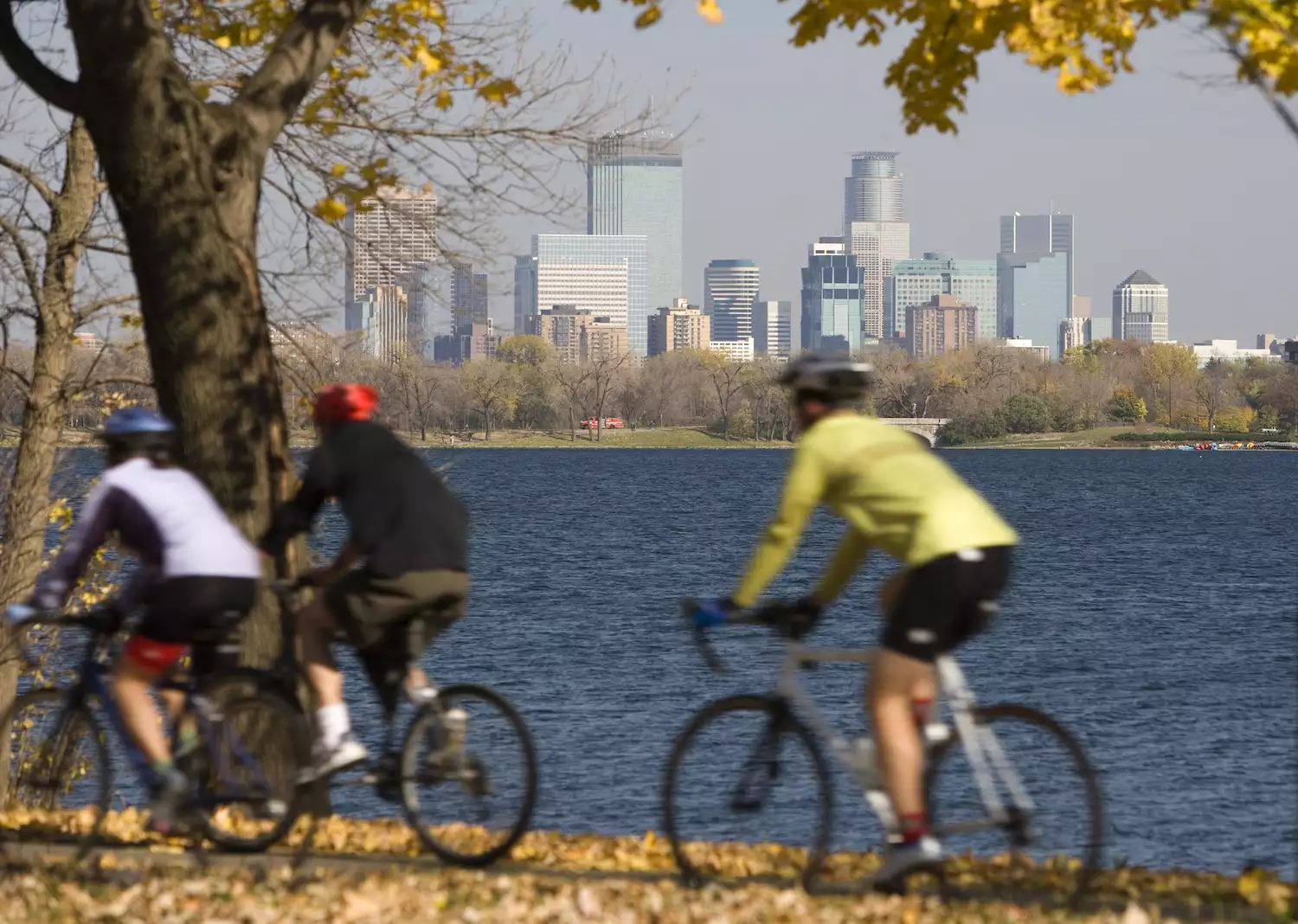 Three bicyclists ride past a waterfront in Minneapolis