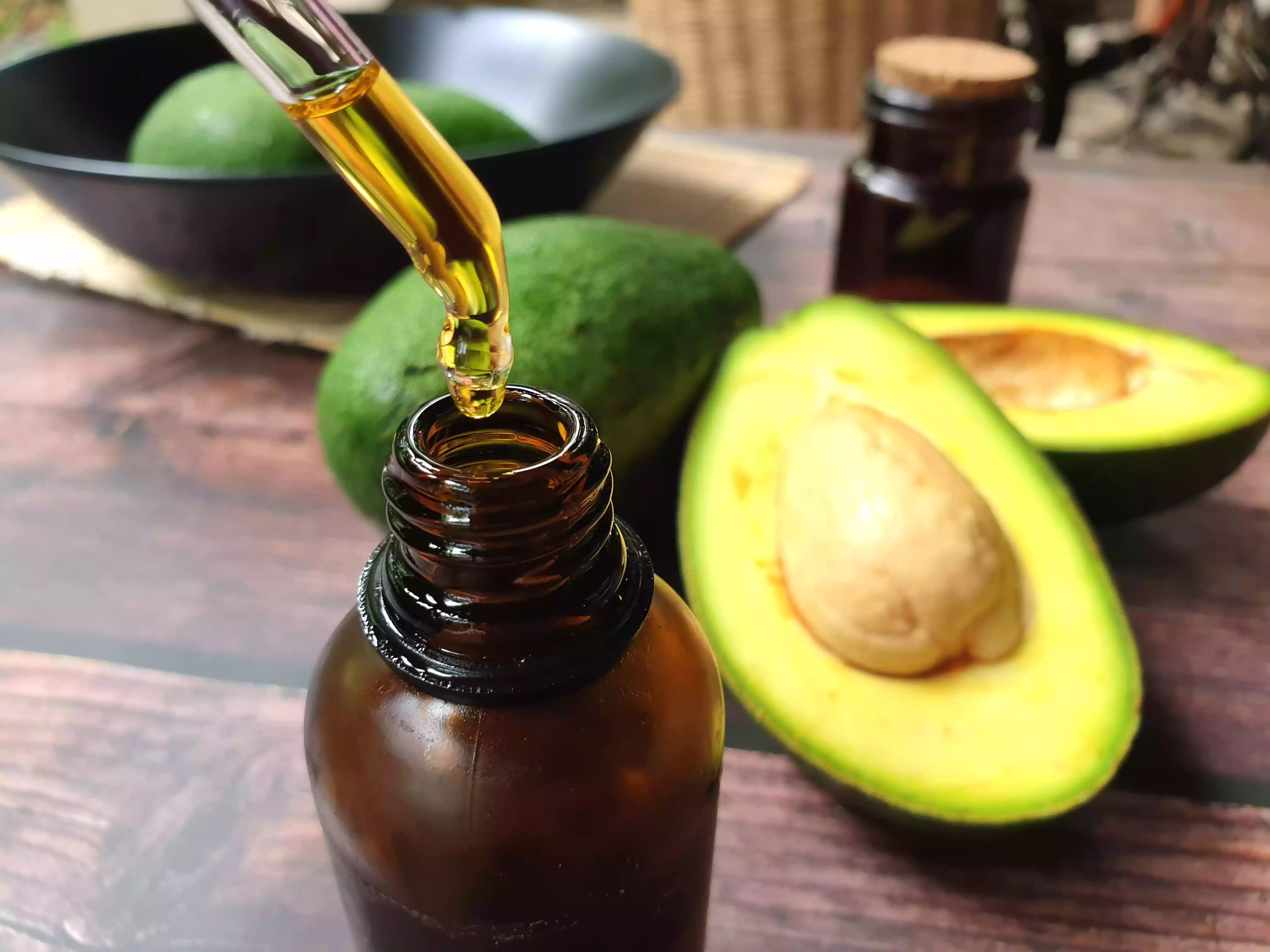 Avocados And Avocado Oil On Wooden Table