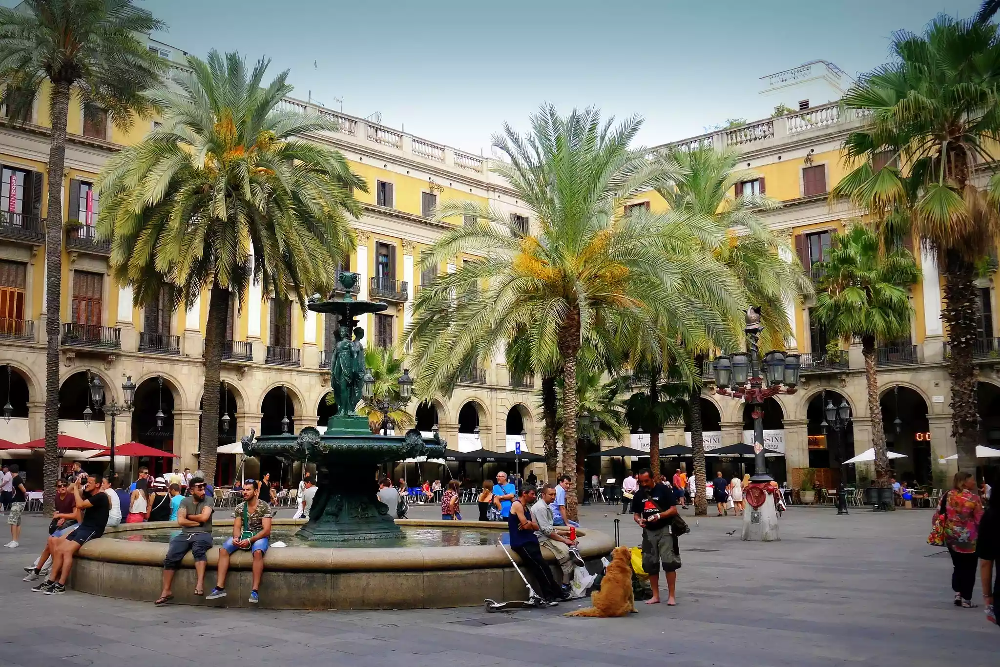 People sitting around fountain in Plaça Reial, Barcelona