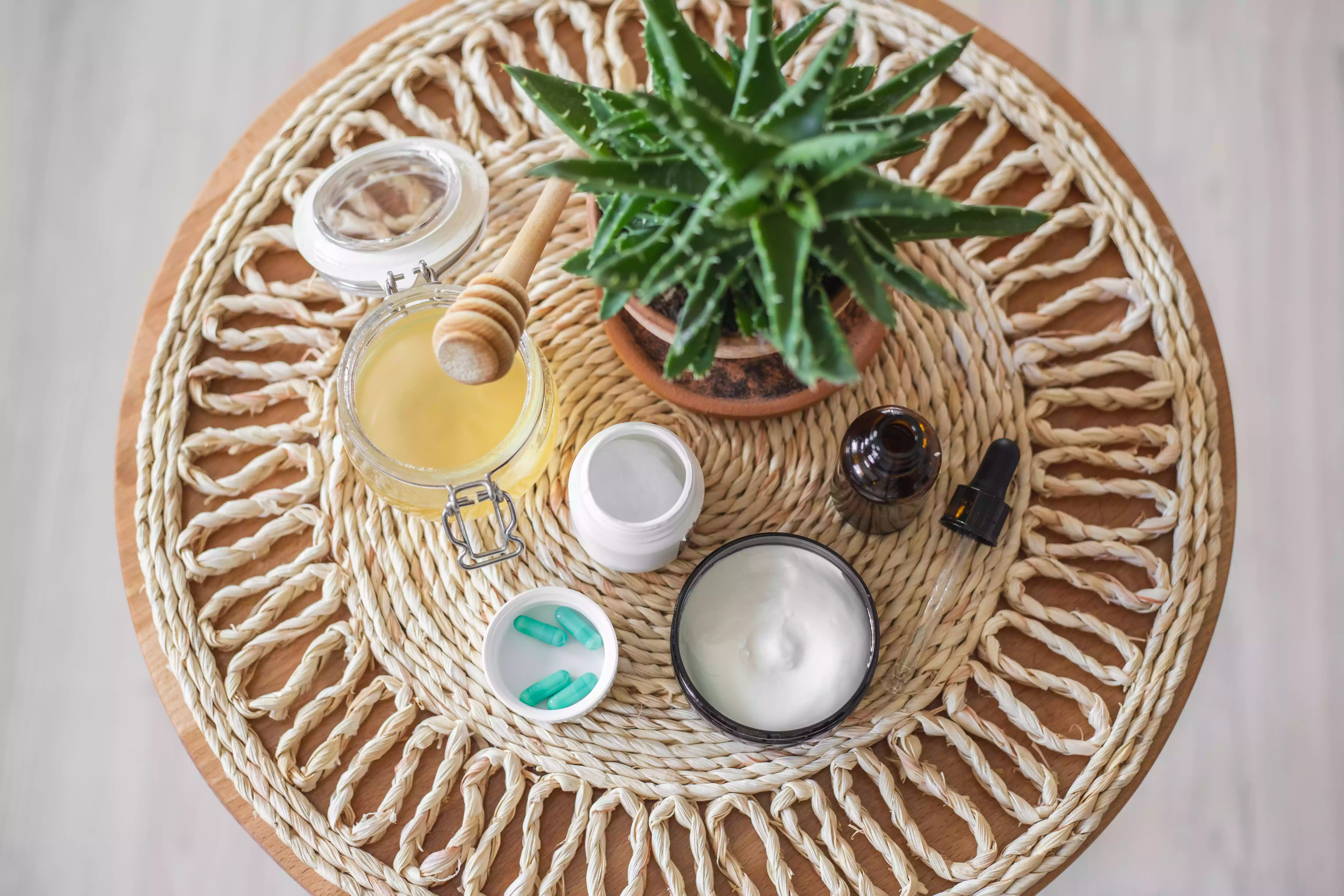 honey, coconut oil, and vitamin E capsules for dry skin displayed on round table
