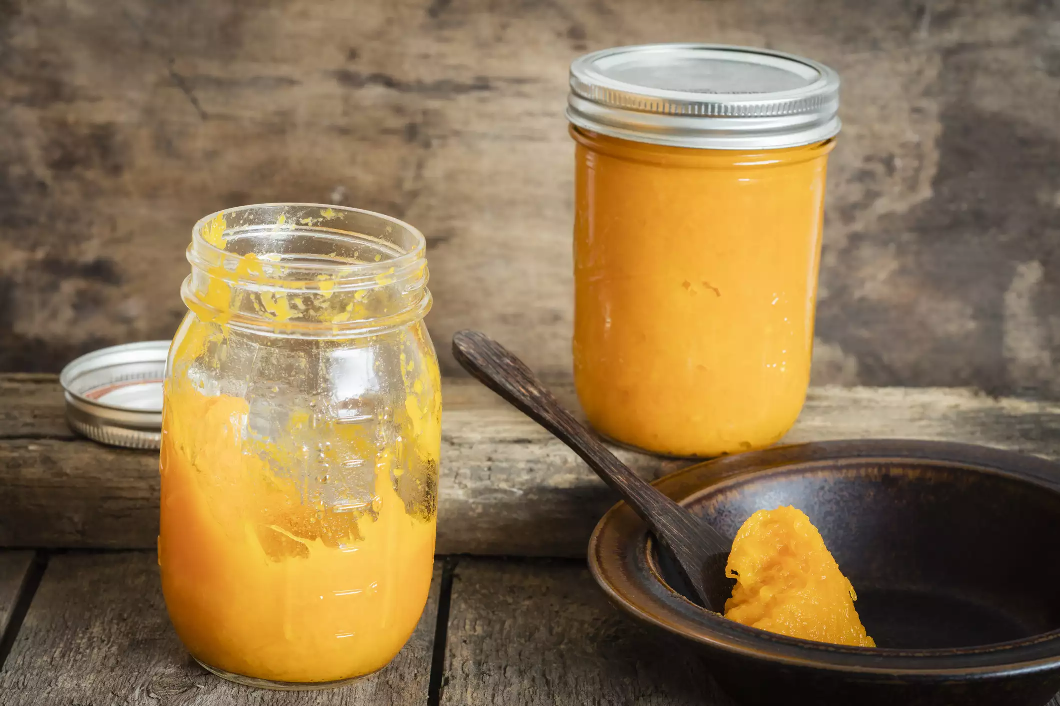 Pumpkin puree in a glass mason jars and spoon in rustic setting.