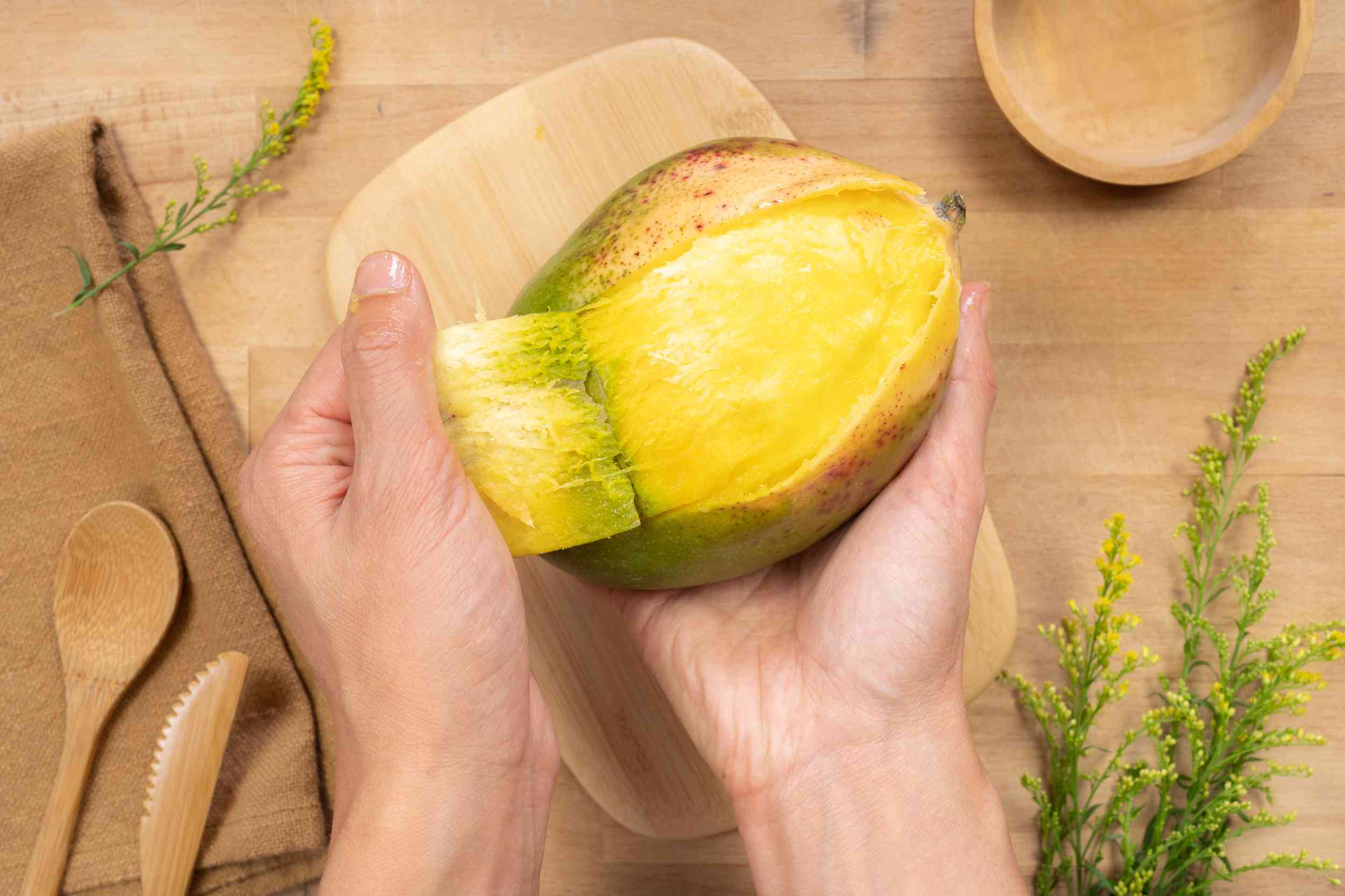 la mano pela la capa superior de la piel del mango fresco para utilizarla como mascarilla AHA