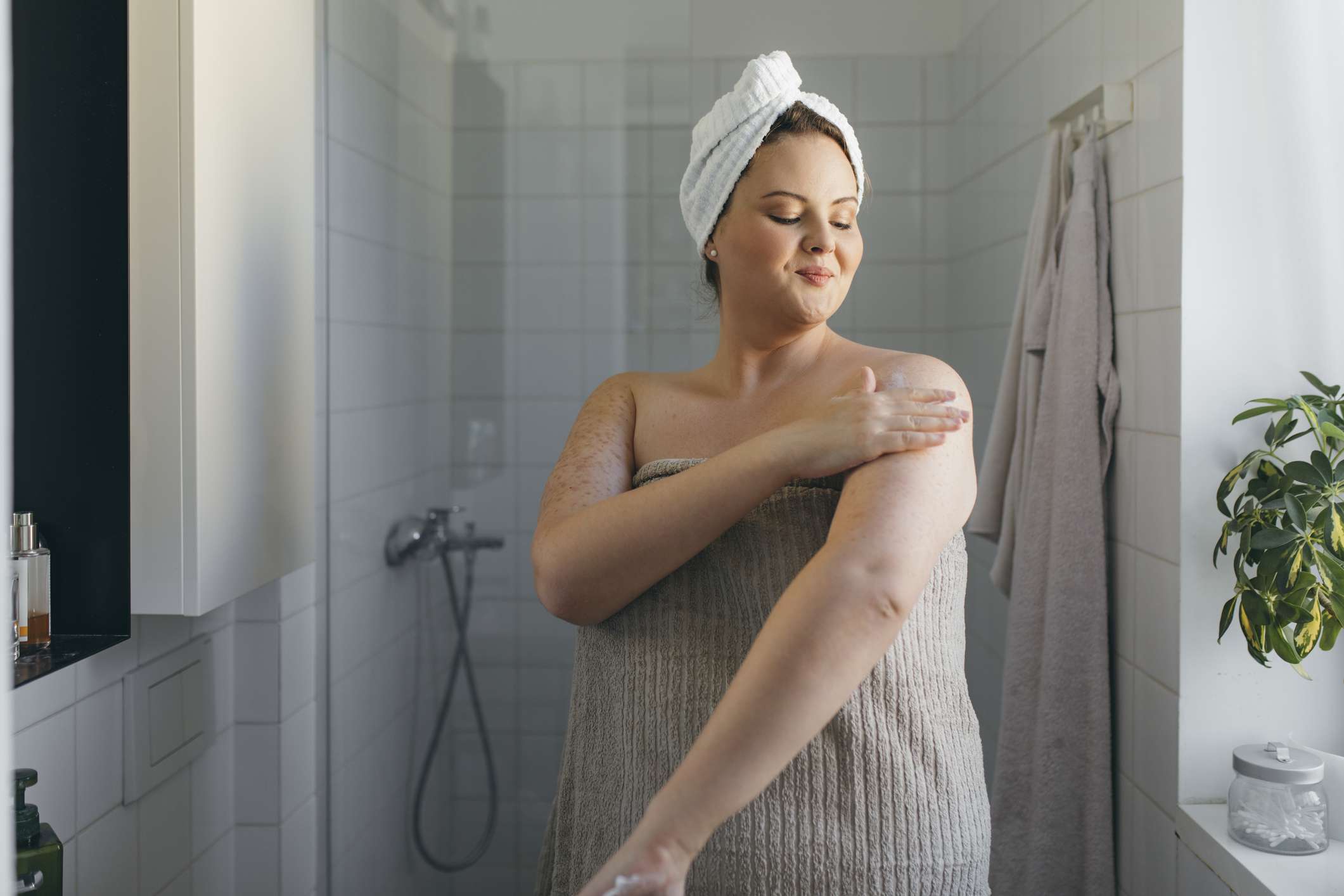 Persona con una toalla aplicando crema hidratante en los brazos