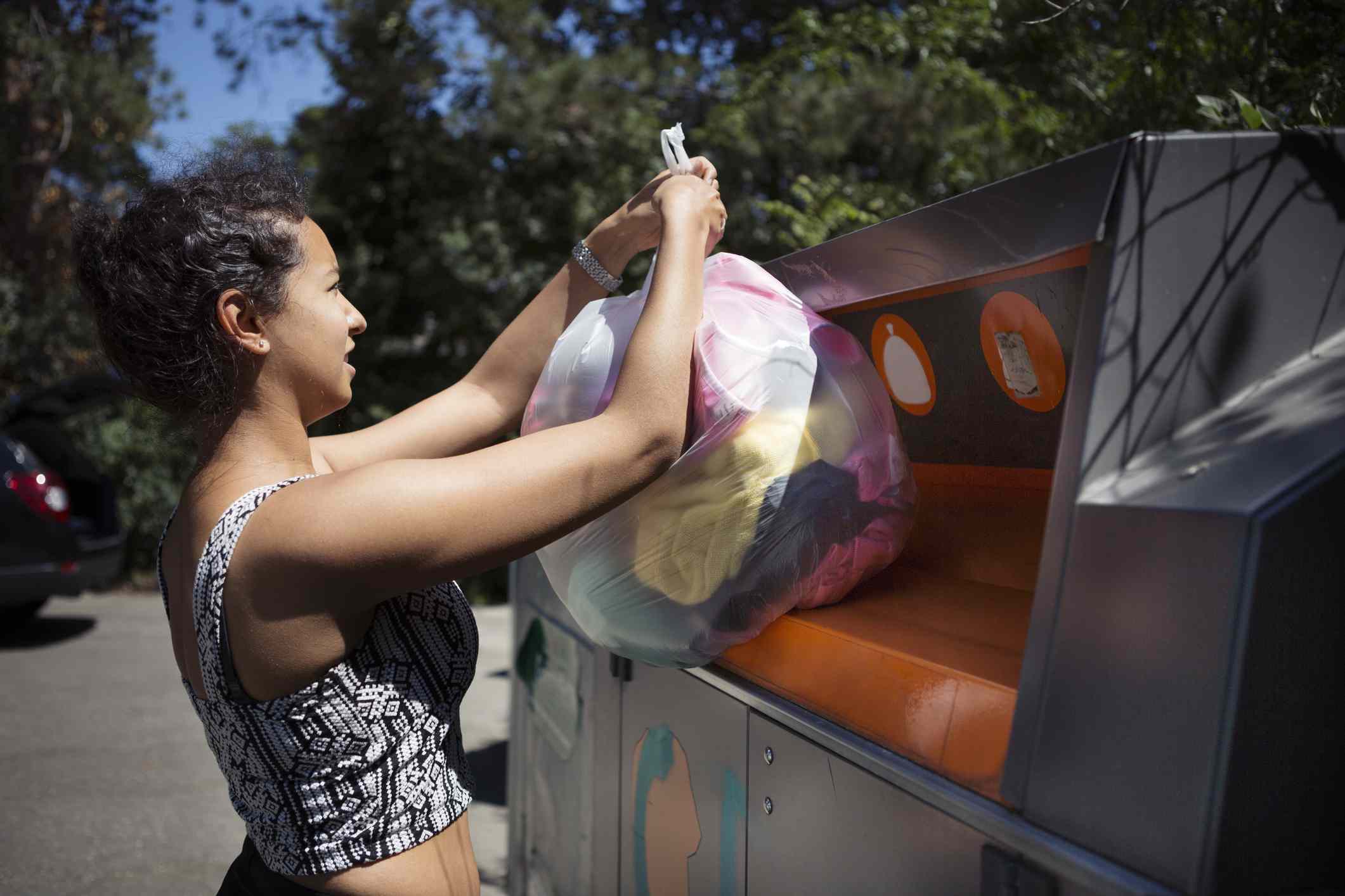 Persona depositando una bolsa de ropa en el contenedor de reciclaje