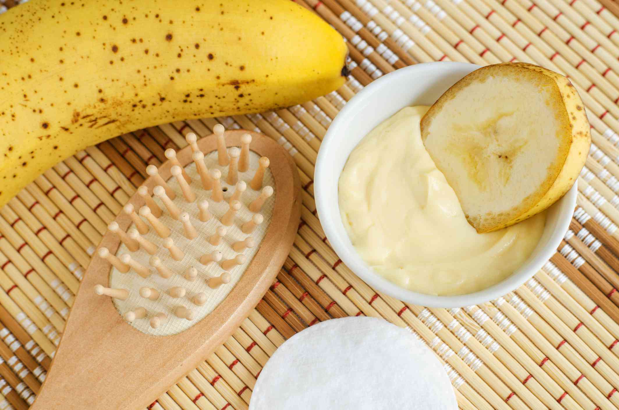 Tazón de puré de plátano con plátano entero y cepillo para el pelo