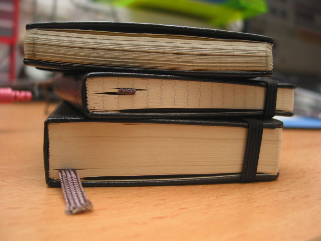 Pila de tres cuadernos moleskine sobre una mesa