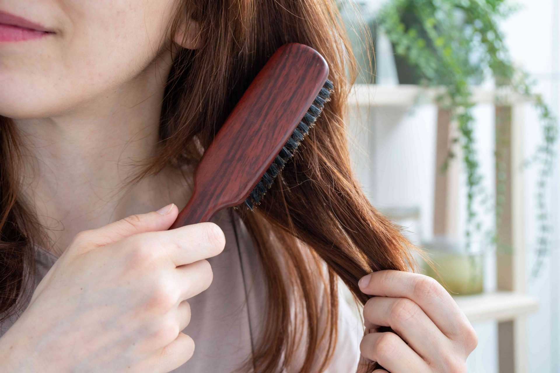 imagen de cerca de una mujer cepillándose el pelo largo con un cepillo de madera natural y cerdas