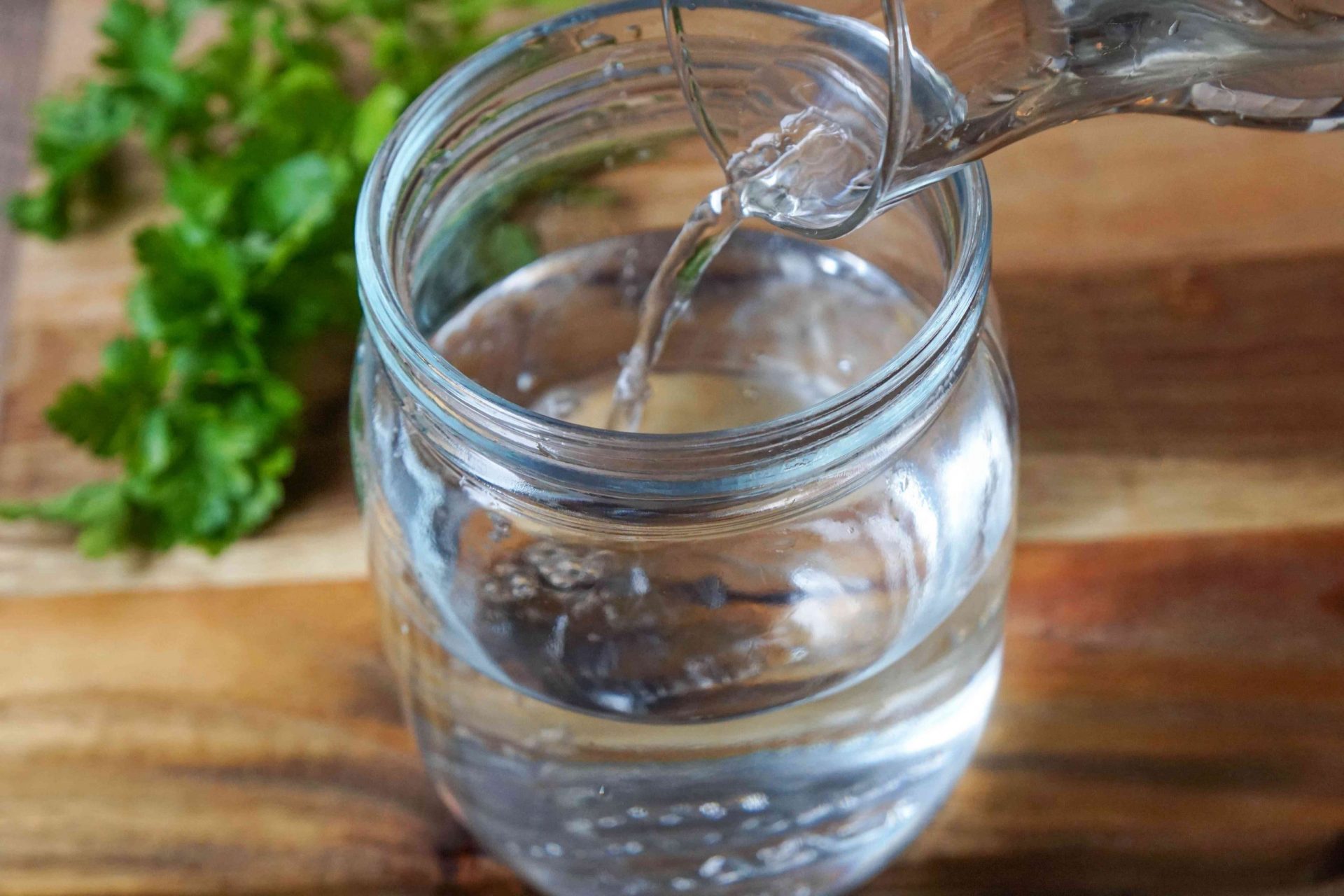 el agua se cambia regularmente en el tarro de cristal para mantener el perejil fresco mientras se almacena