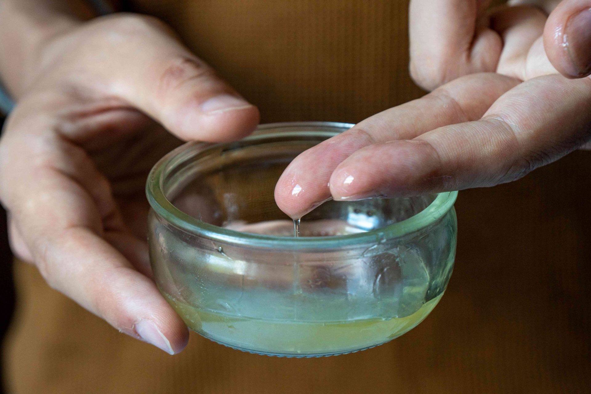 foto de cerca de las manos sumergiendo los dedos en la mascarilla de aloe vera-limón-miel en un cuenco de cristal