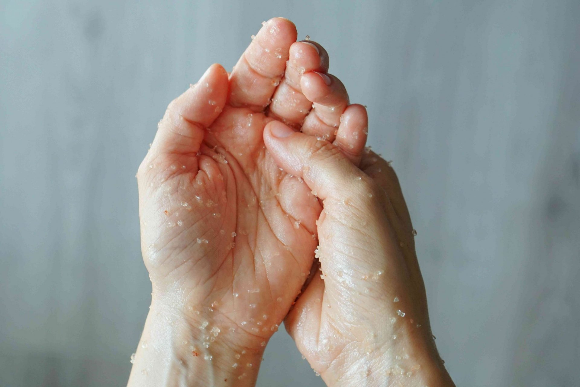 dos manos se frotan la mezcla de exfoliación casera con sal