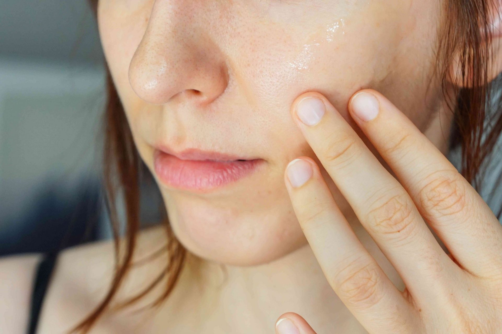 mujer se aplica aceite directamente en las mejillas después del baño