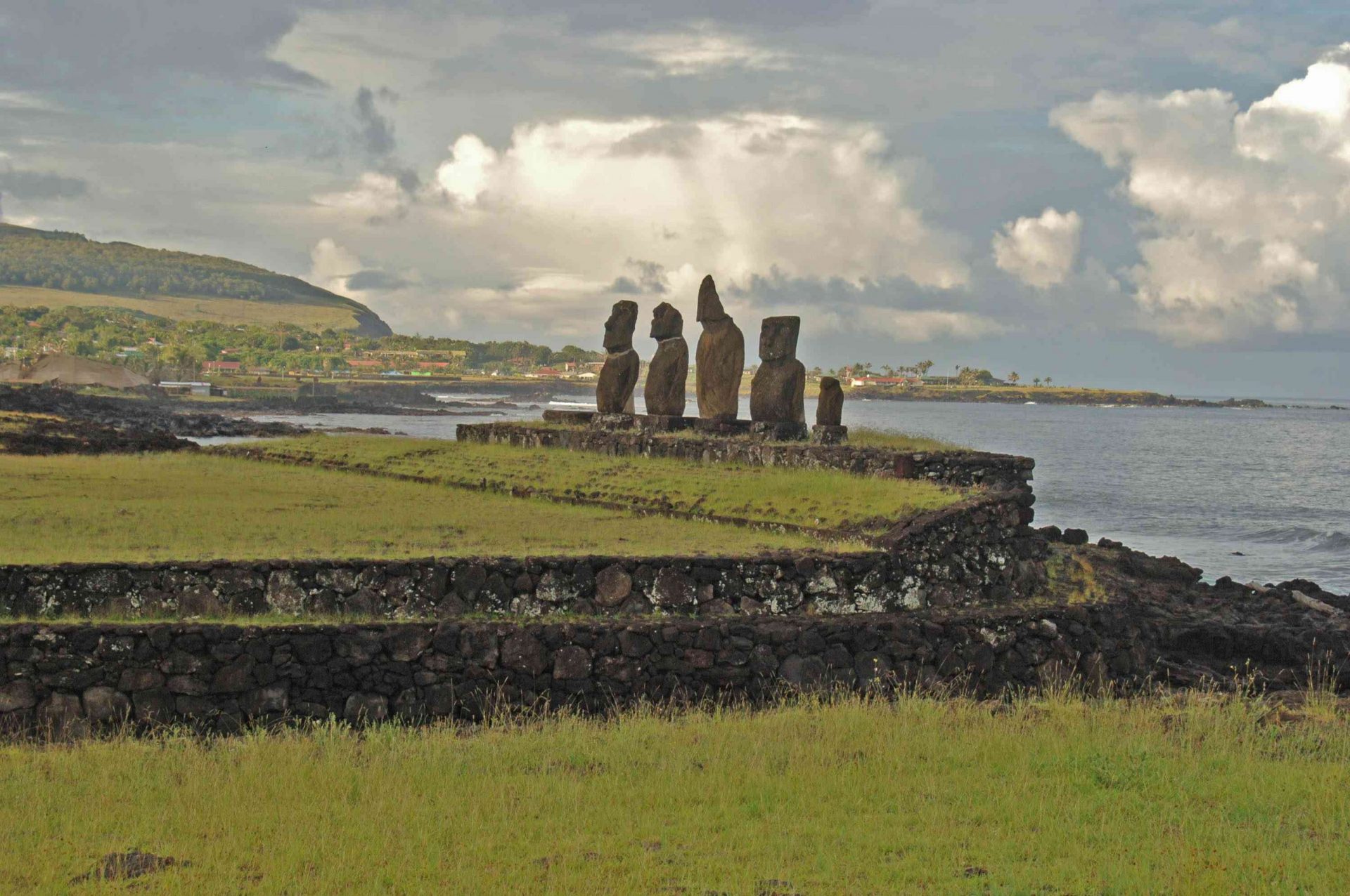 Estatuas de piedra o moai construidas en un acantilado de hierba con vistas al agua en la Isla de Pascua