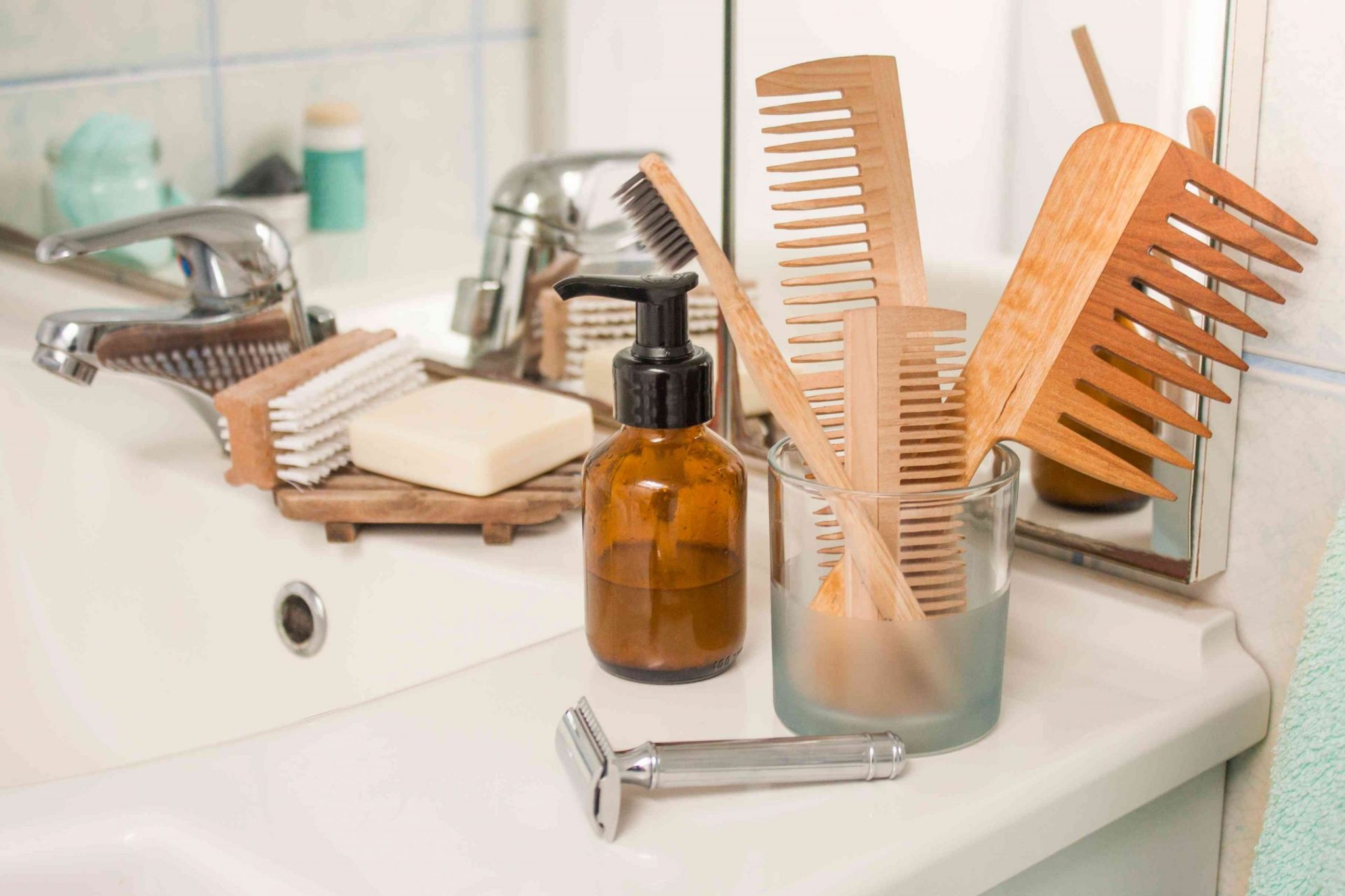Productos de residuo cero en el mostrador del baño, incluyendo peines de bambú, una maquinilla de afeitar de metal, un cepillo de dientes de bambú, una pastilla de jabón y mucho más