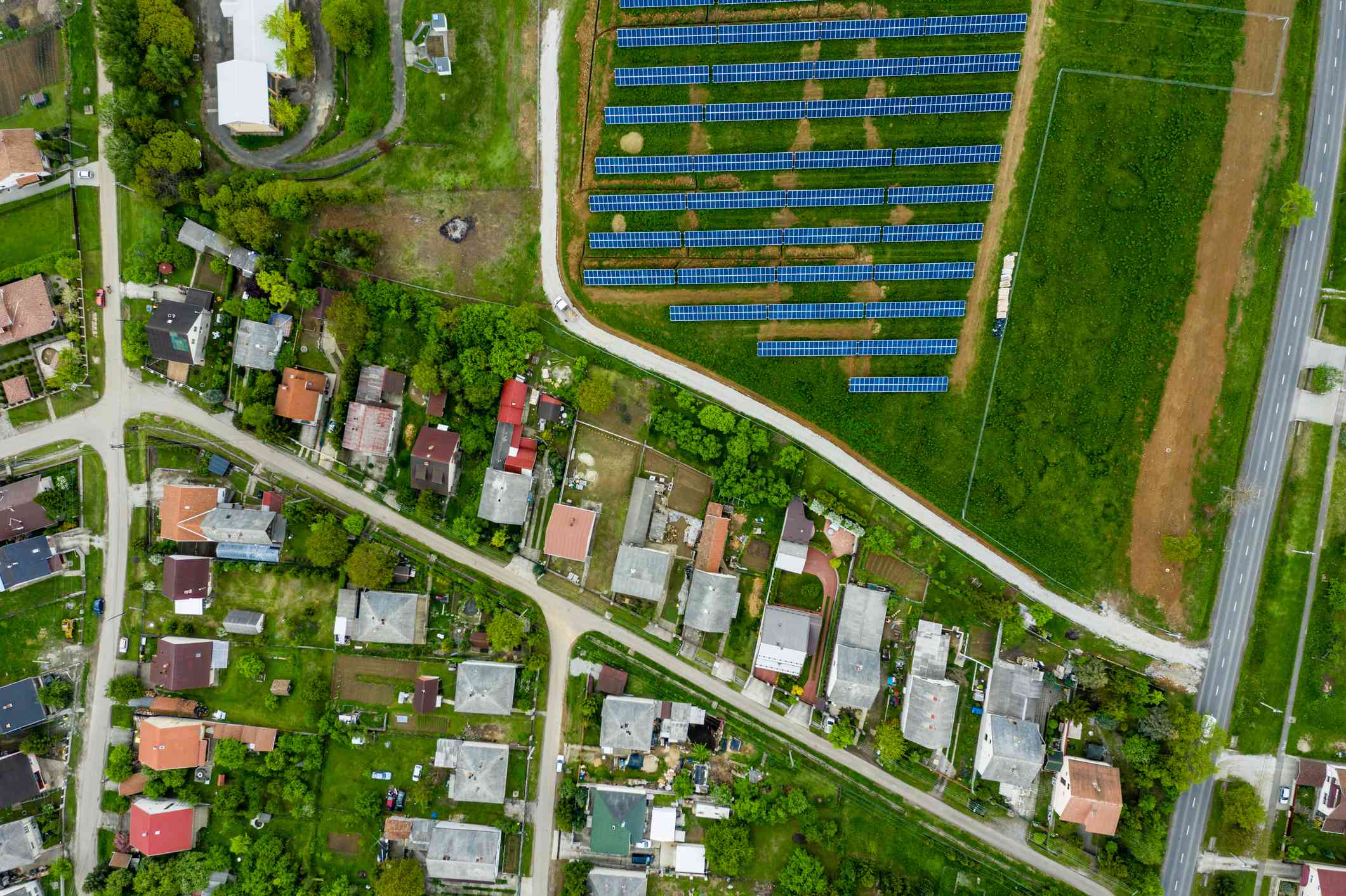 Una vista aérea muestra una instalación solar en un campo junto a un barrio residencial.