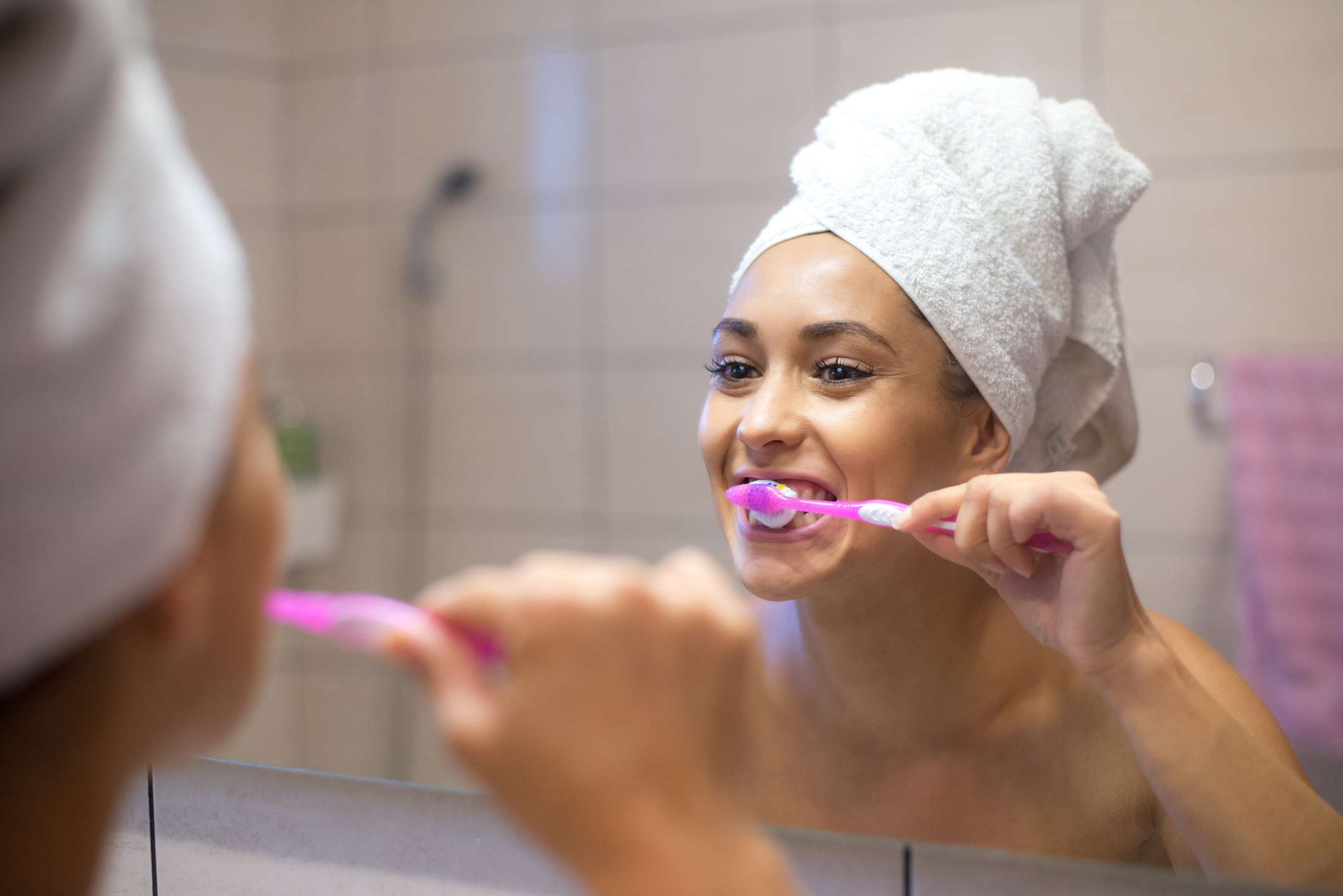 Una mujer cepillándose los dientes mirándose al espejo