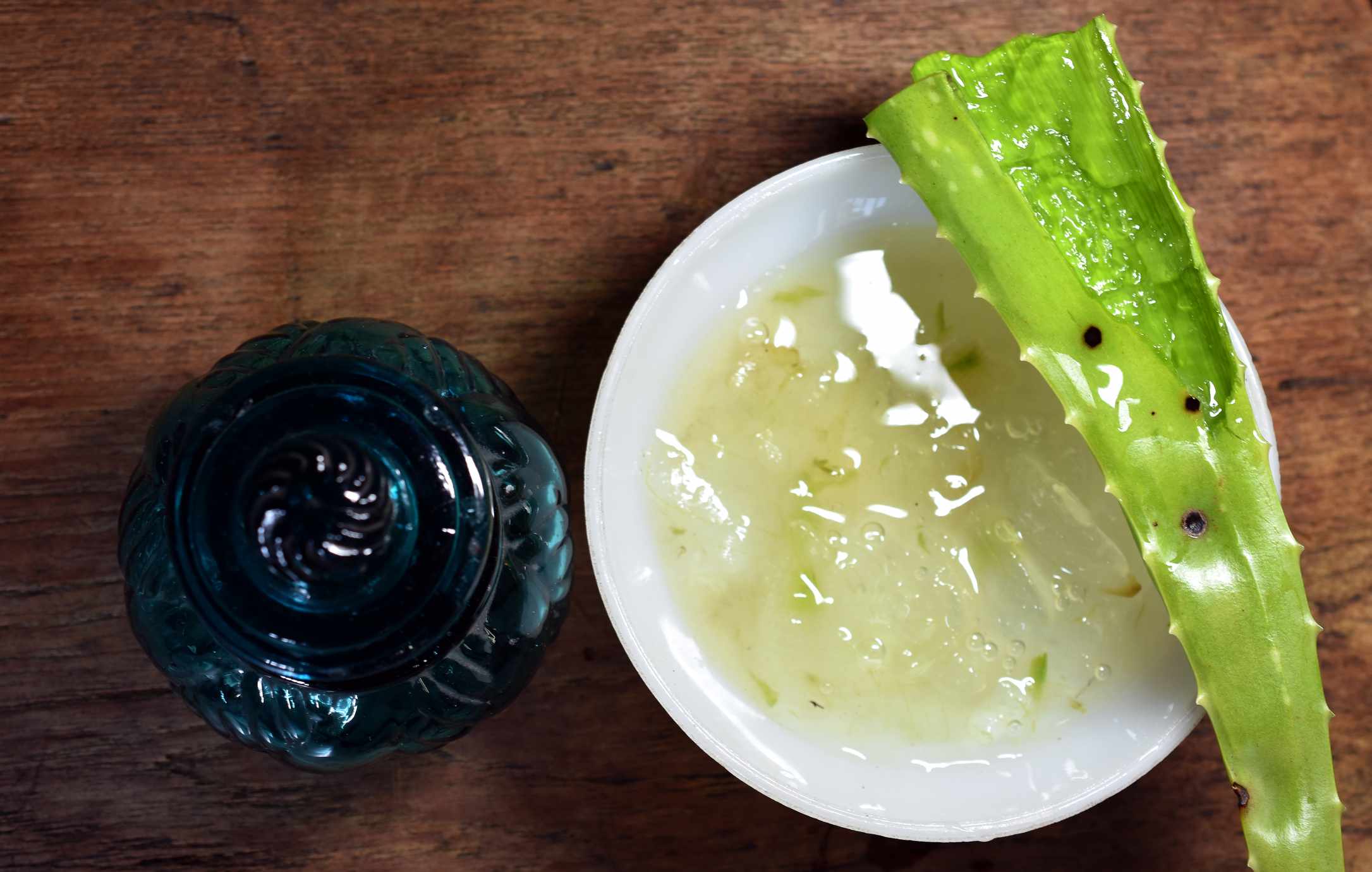 Aloe vera en un plato y un tarro de cristal azul antiguo al lado