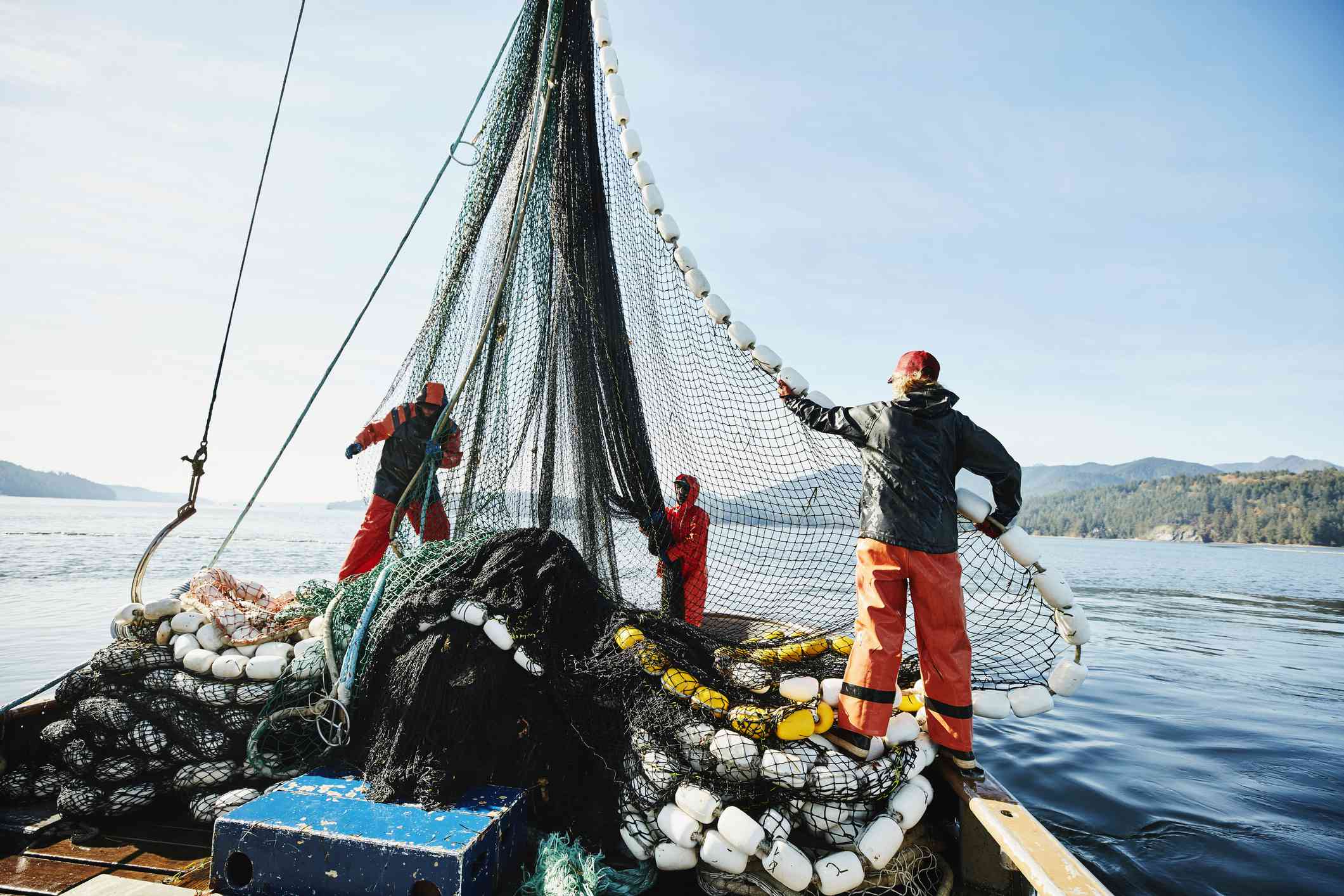 Pescadores maniobrando una red de pesca en un barco de pesca comercial