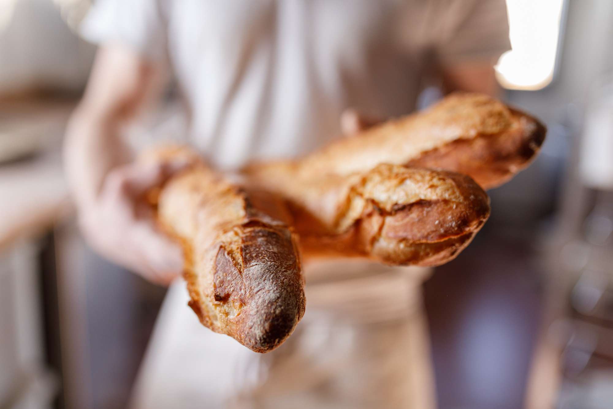 Primer plano de una mano sujetando panes de baguette franceses
