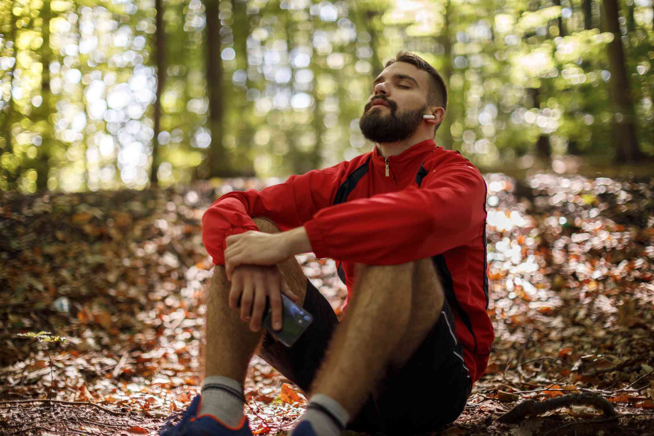 Un hombre blanco con barba se sienta en el bosque y respira el aire fresco