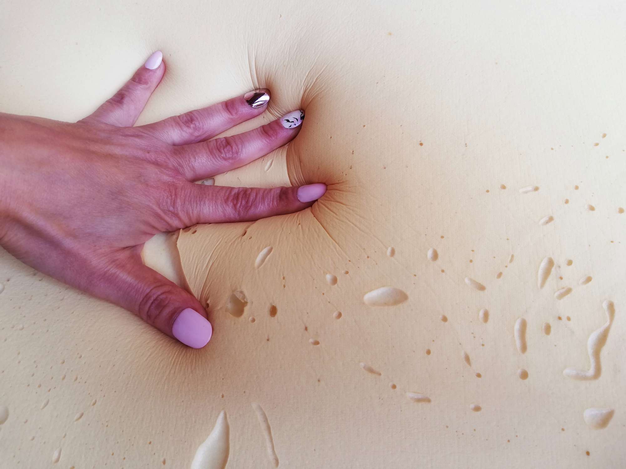 Una mano con las uñas pintadas presiona la espuma de memoria dañada