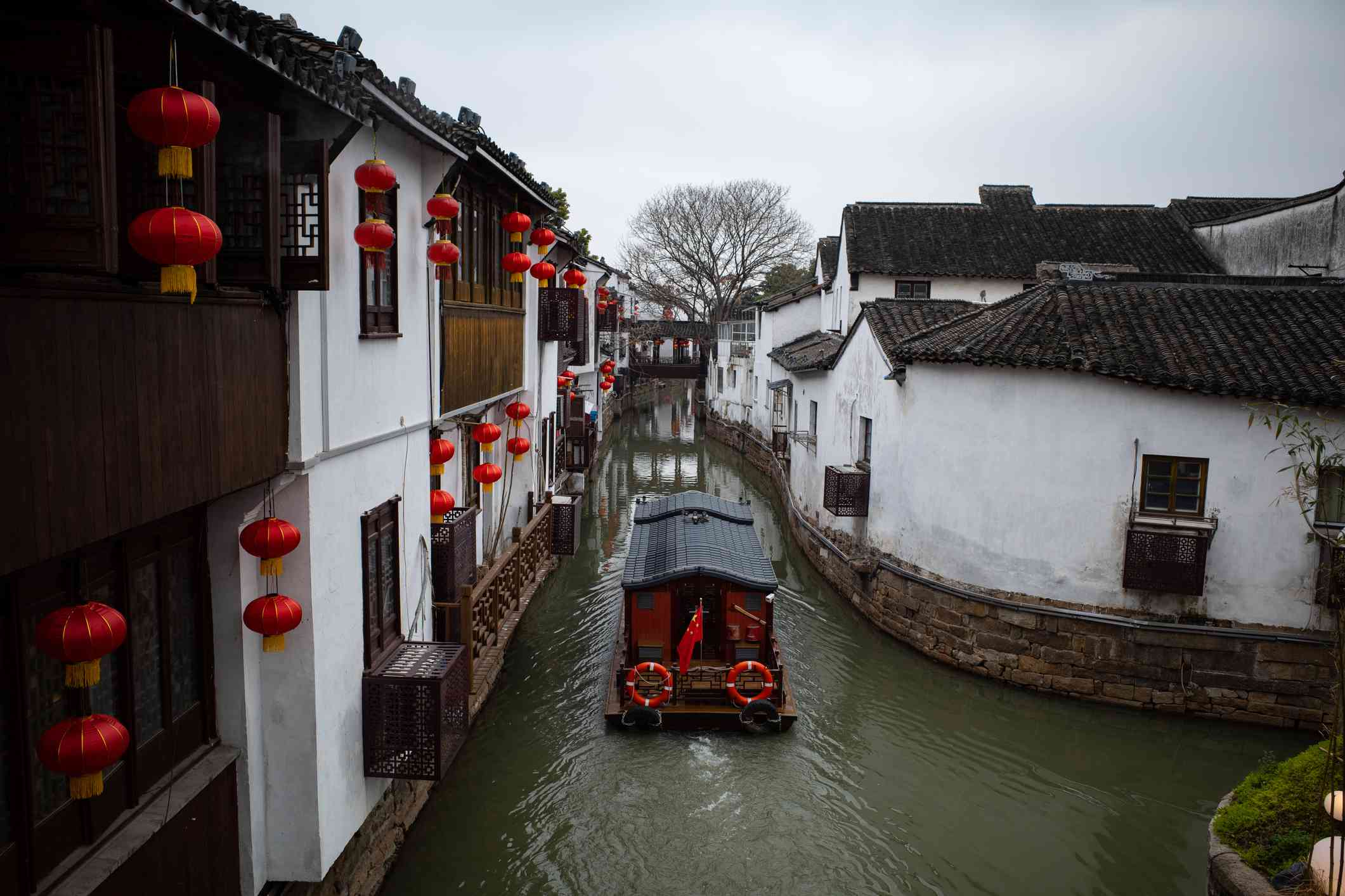 barco negro con ribetes rojos recorriendo el agua en la antigua ciudad acuática de Suzhou