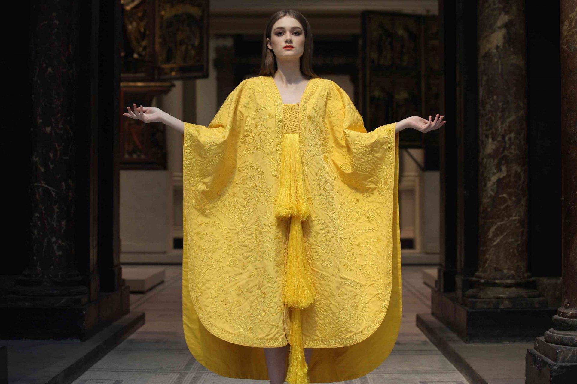 Una modelo con una capa amarilla hecha con seda de araña