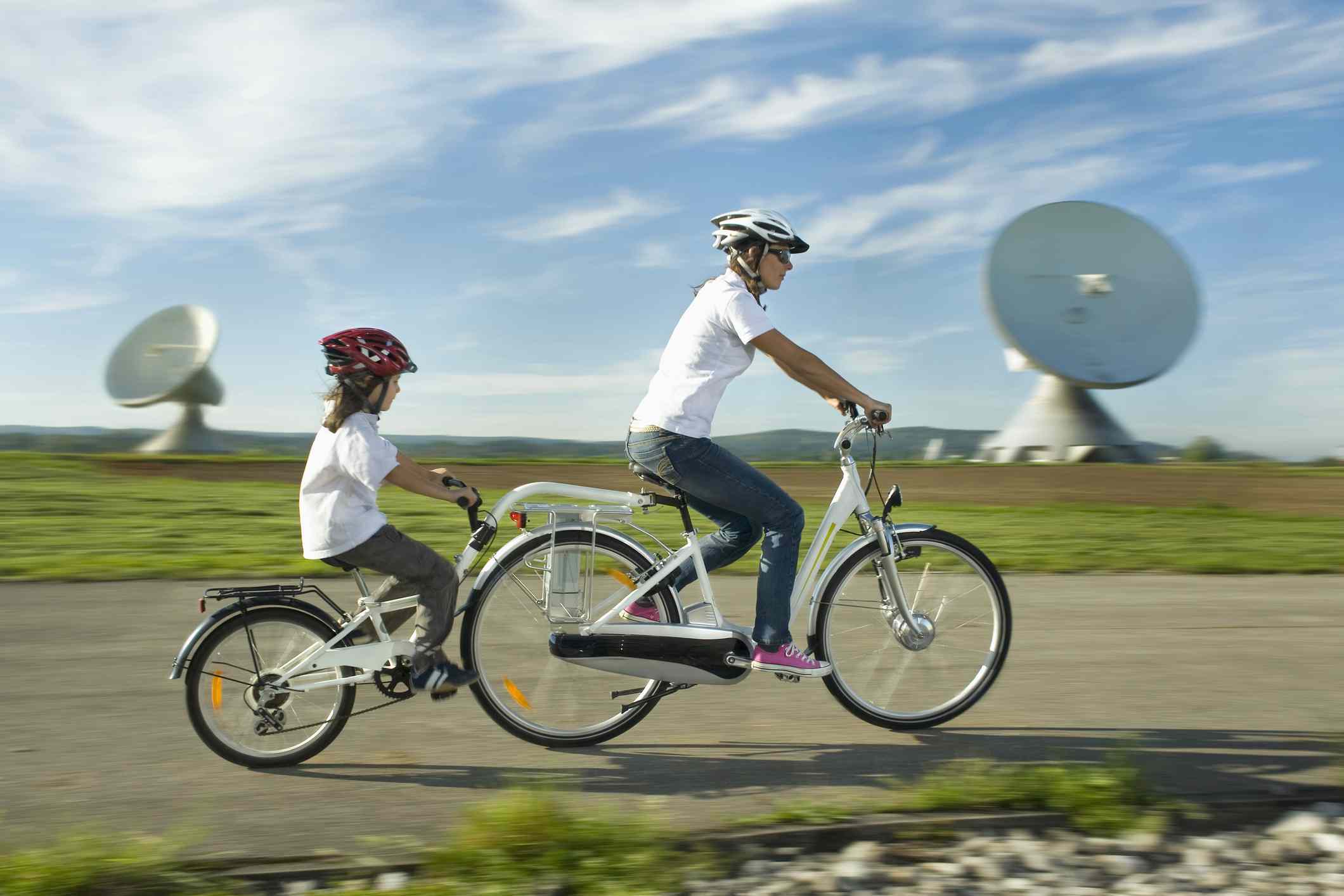 Alemania, Baviera, Raisting, Mujer con niña montando en bicicleta eléctrica cerca de la estación de radio