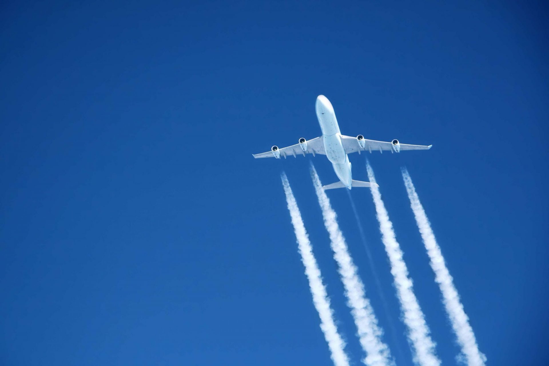 Avión creando nubes de estela en el cielo azul