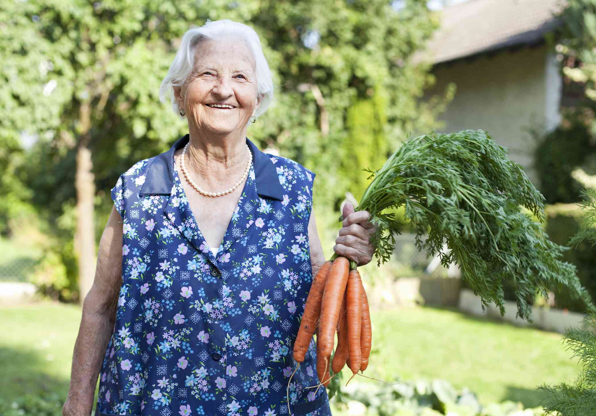 Una anciana sostiene un manojo de zanahorias con una sonrisa