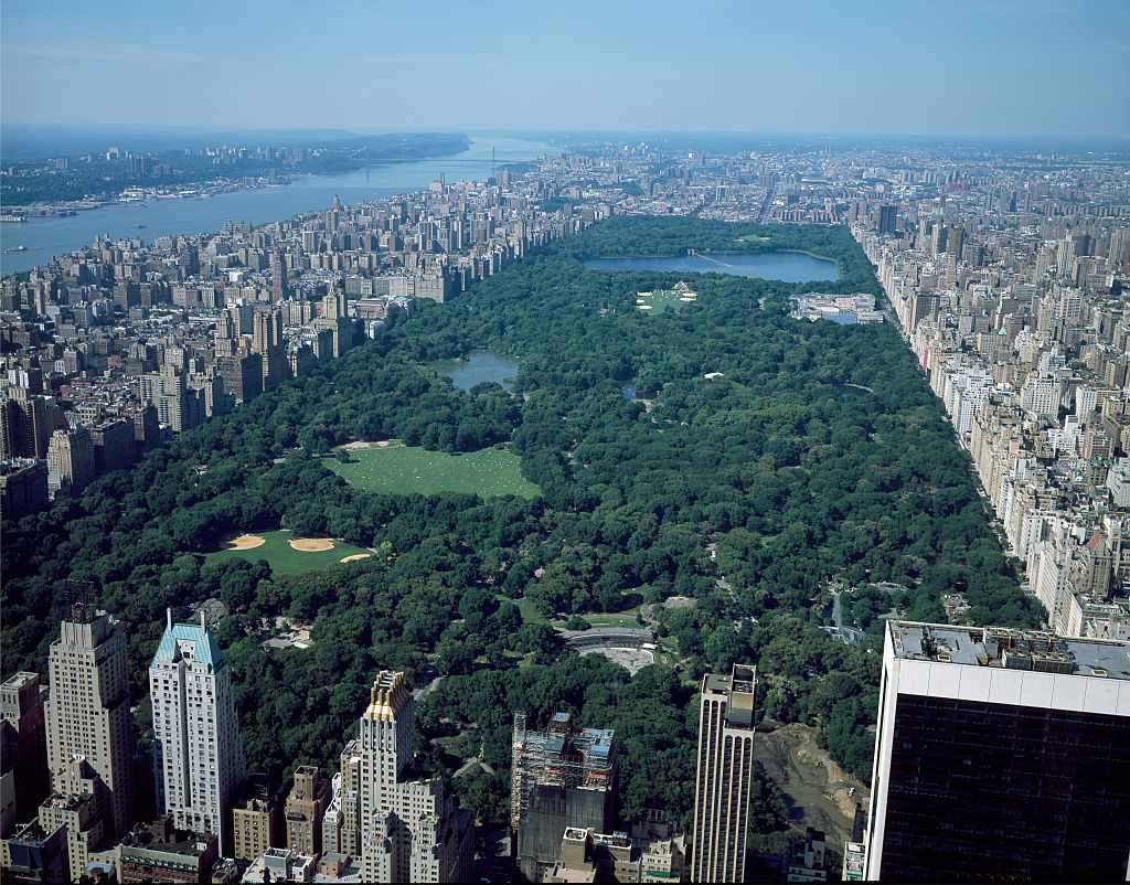 Vista aérea de Central Park en Nueva York con el parque verde rodeado de edificios y vistas del río en la distancia