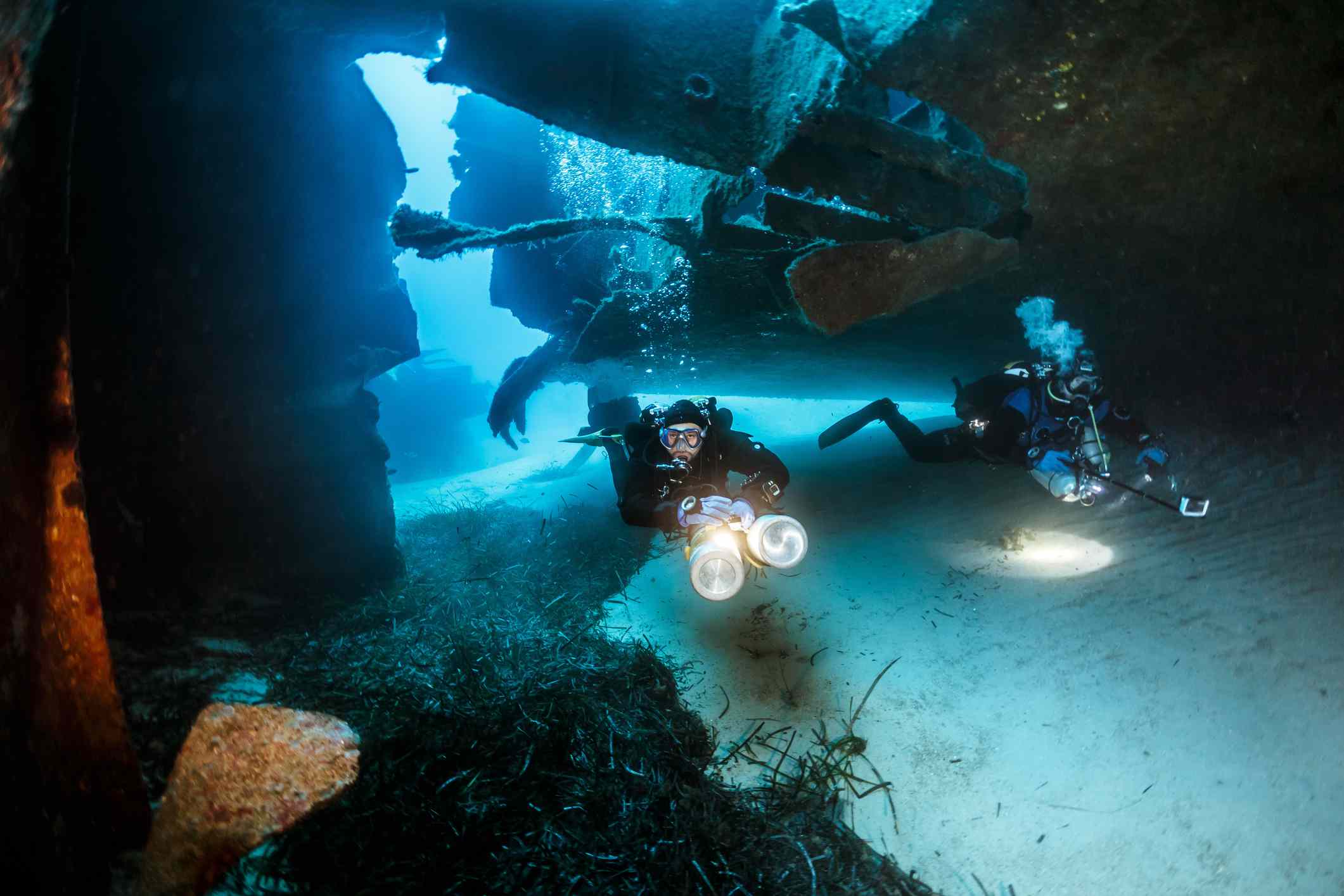 Dos submarinistas con luces brillantes nadando entre los restos del naufragio Um El Faroud en Malta