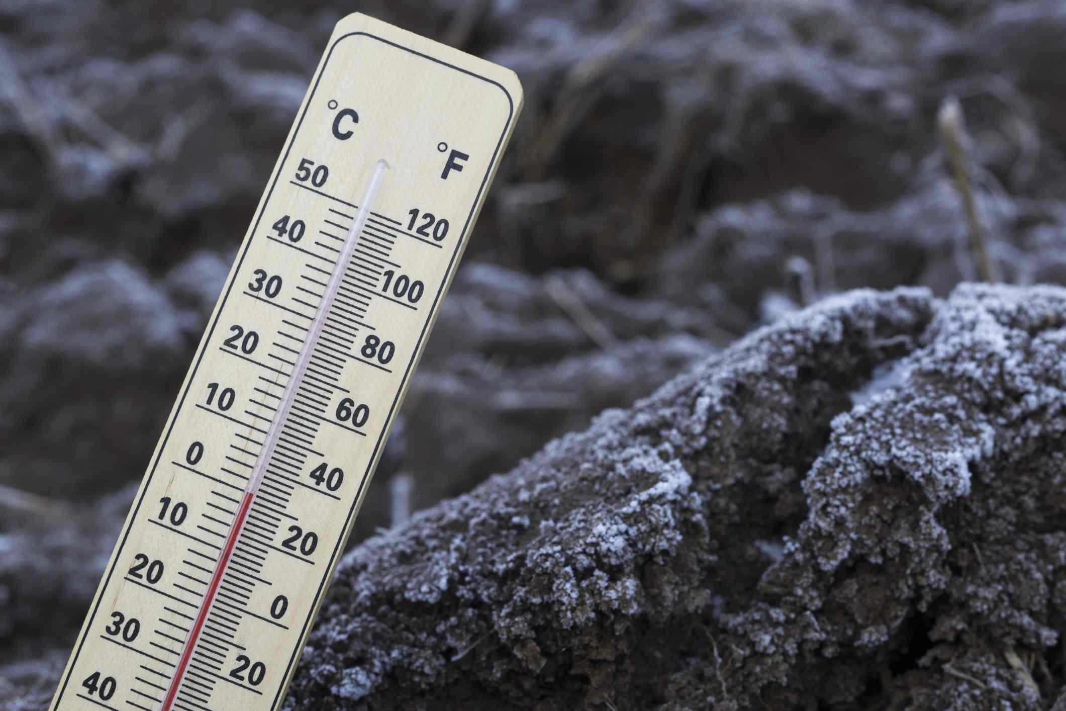 Un termómetro mide la temperatura del suelo congelado