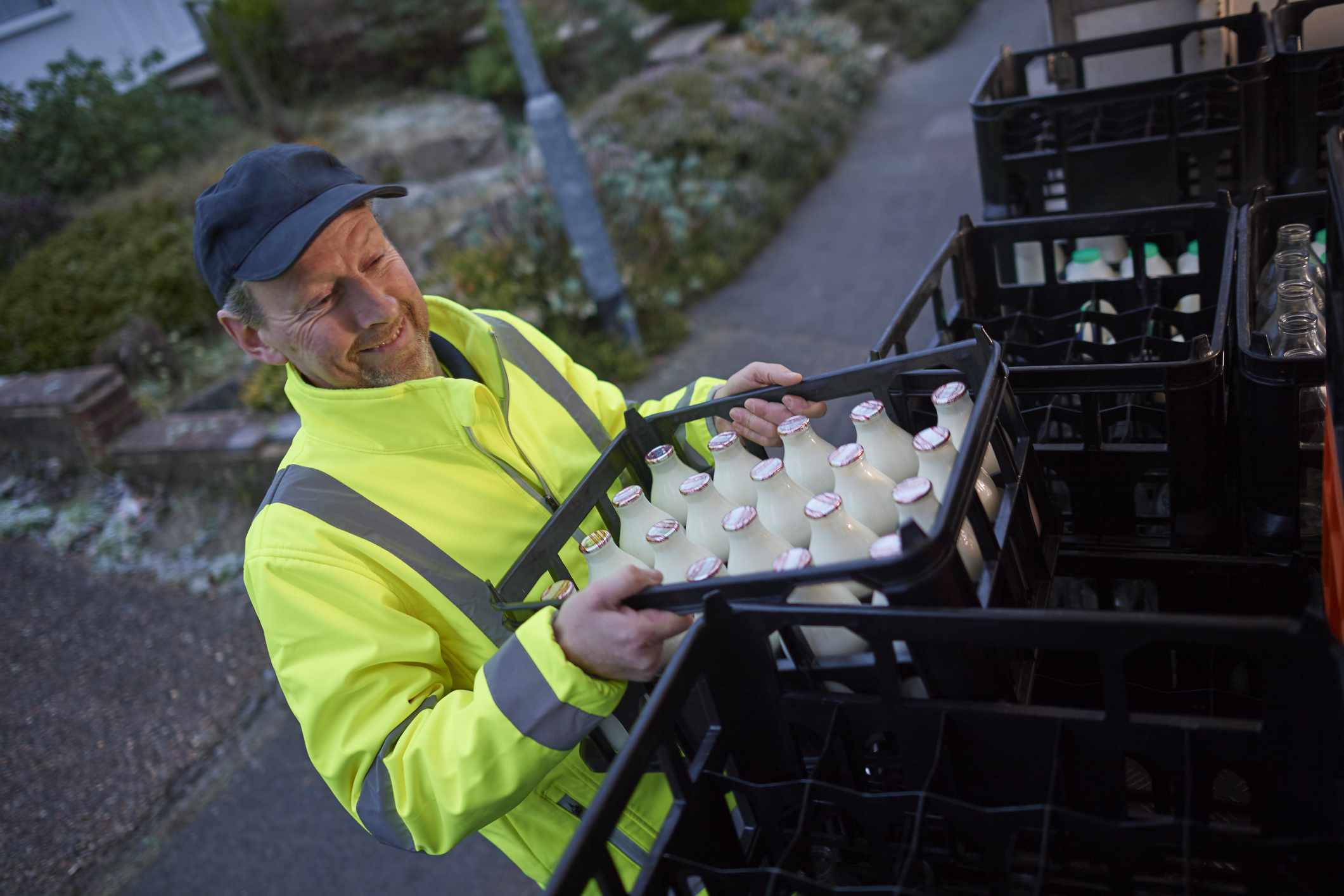 Un lechero transporta una caja llena de botellas de leche de un camión