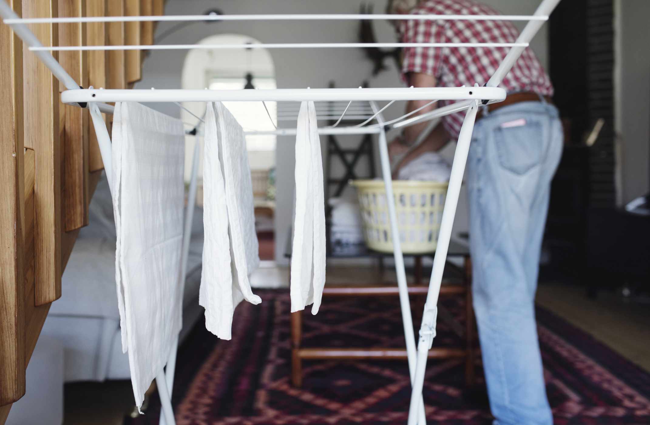 Una persona colgando ropa blanca en un tendedero de interior