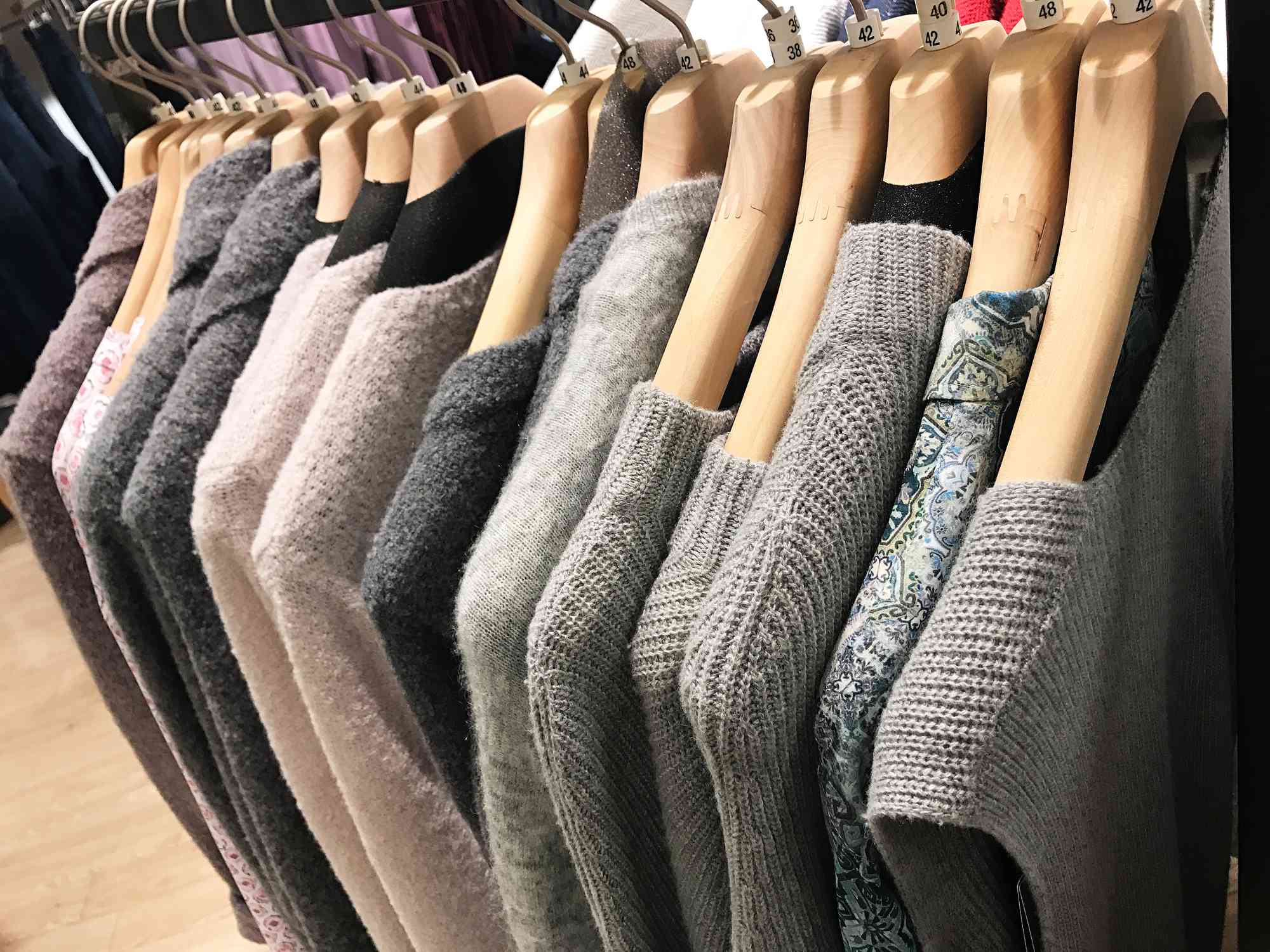Suéteres grises y crema en un estante de una tienda