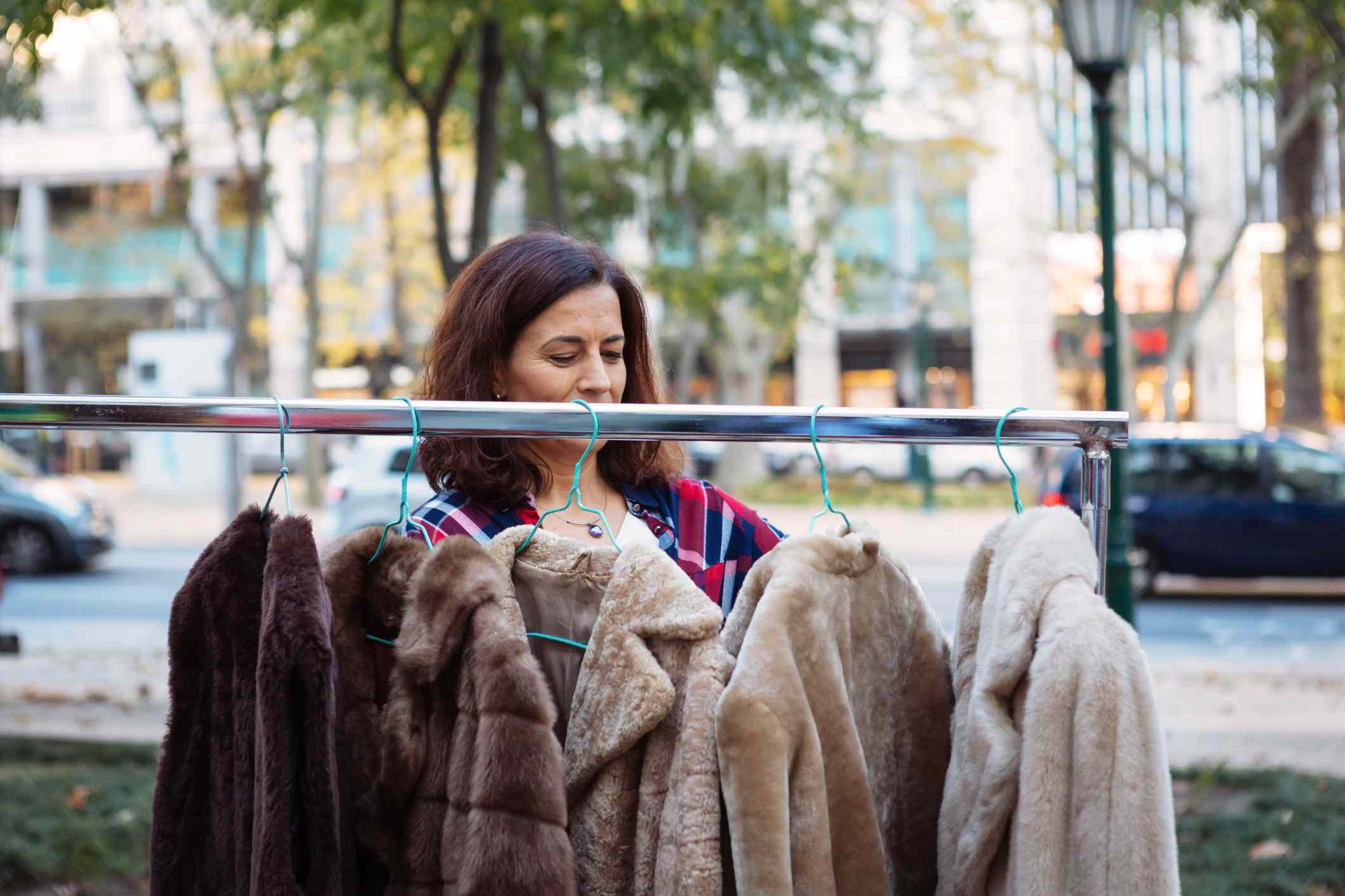 Mujer madura mirando abrigos de piel en la ciudad en el mercado