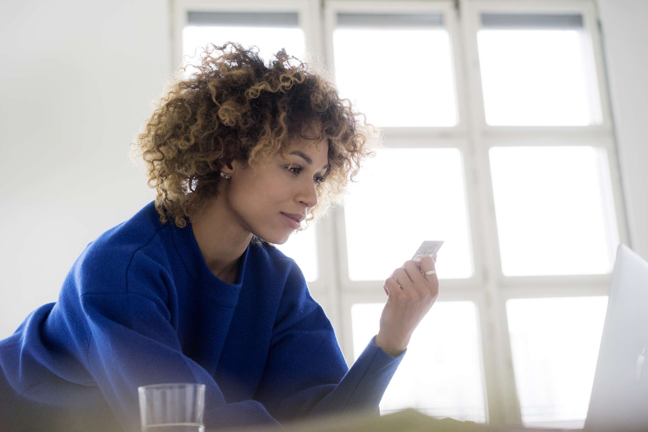 Una mujer negra con el pelo rizado utiliza su tarjeta de crédito en Internet