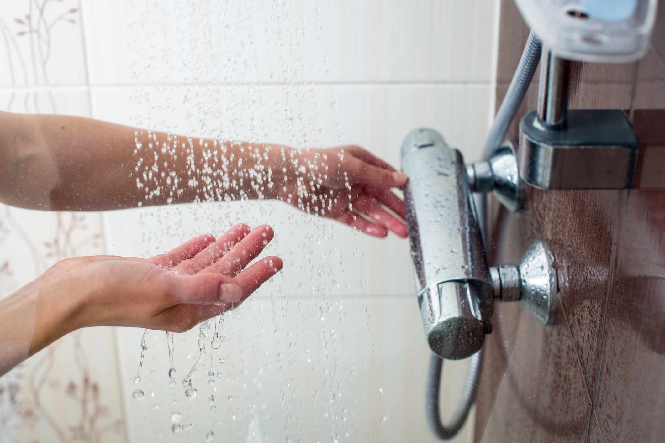 Una mujer comprueba la temperatura del agua en la ducha