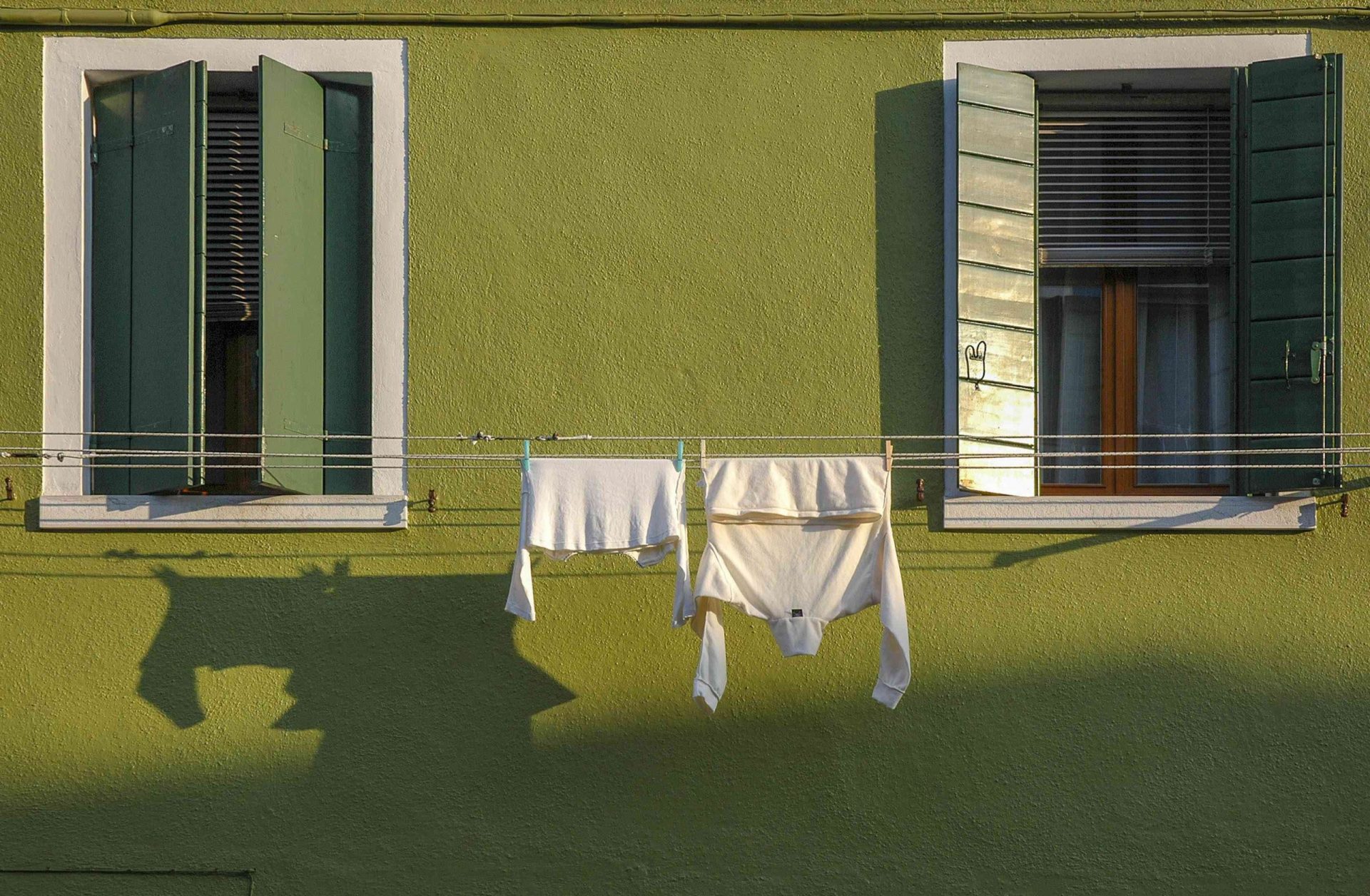 La ropa se seca al sol en un tendedero colgado entre dos ventanas
