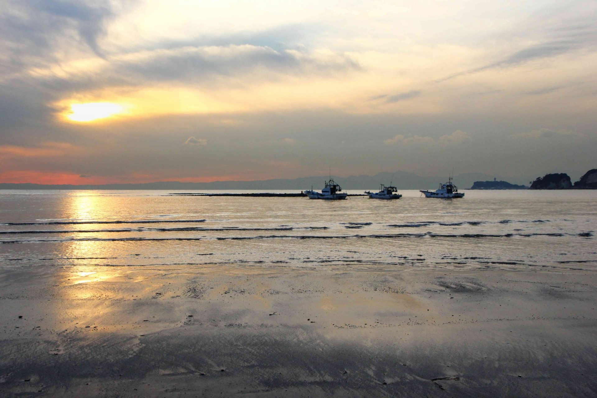 3 barcos en el horizonte derecho mientras el sol se pone en la playa del océano