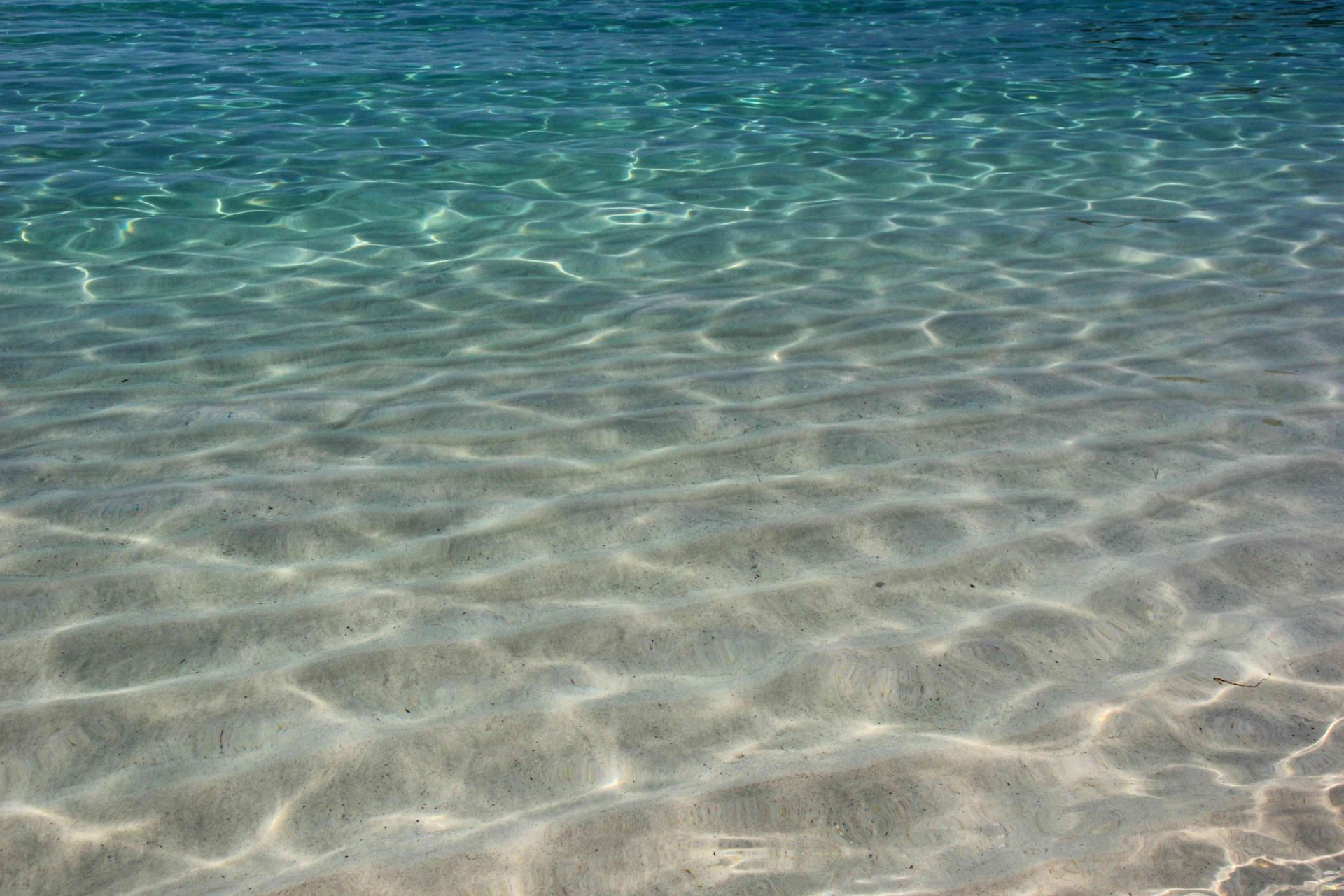 agua oceánica poco profunda de color turquesa con arena tostada