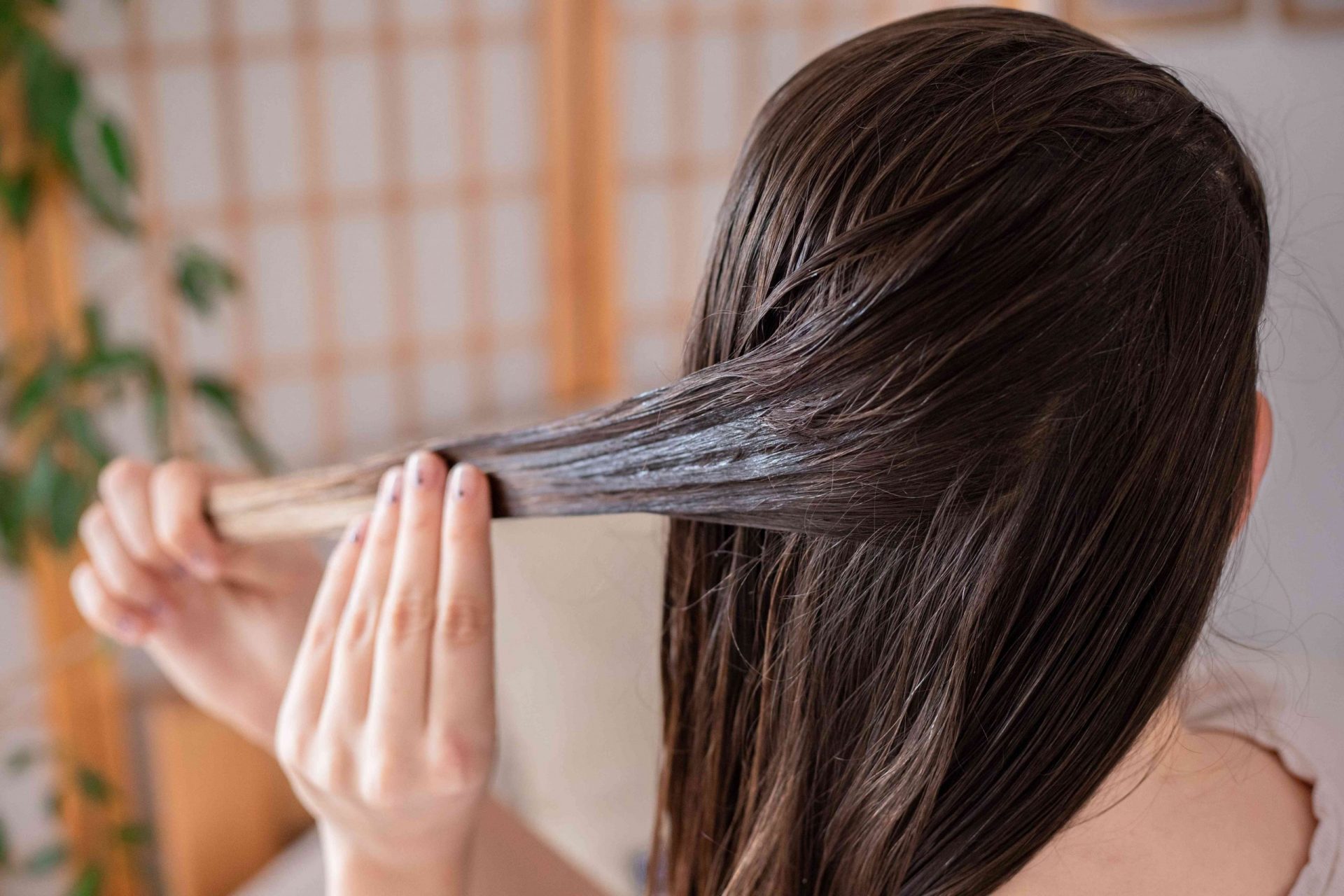 parte trasera de la cabeza de una mujer mientras aplica el tratamiento de mascarilla diy a los mechones de pelo secos