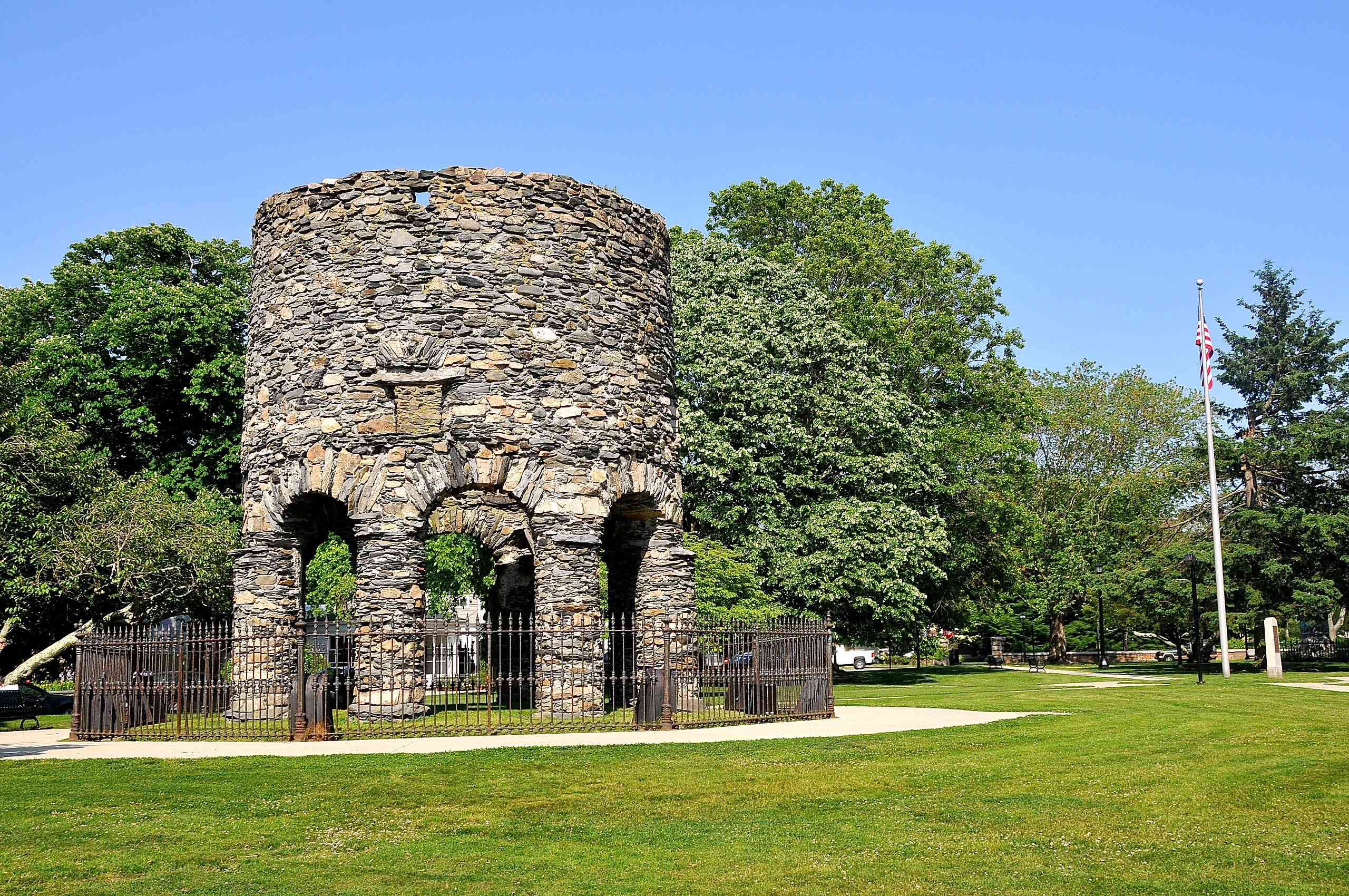 Torre redonda de piedra situada en medio de un parque cubierto de hierba