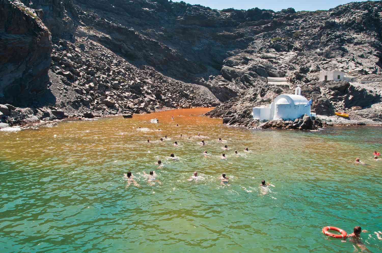 Gente nadando en las aguas de la isla volcánica Palea Kemini