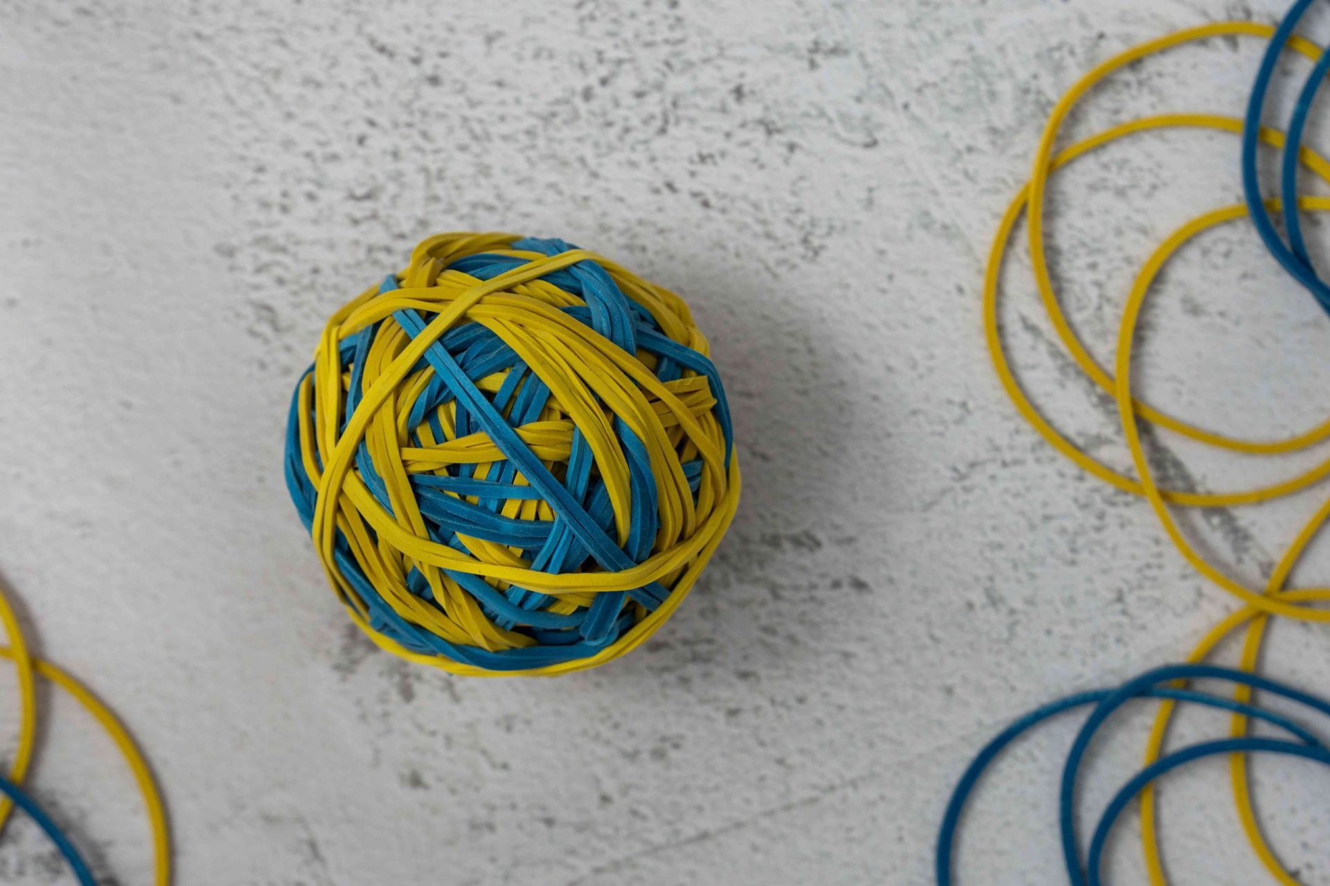 pelota de gomas elásticas amarilla y azul sobre fondo blanco