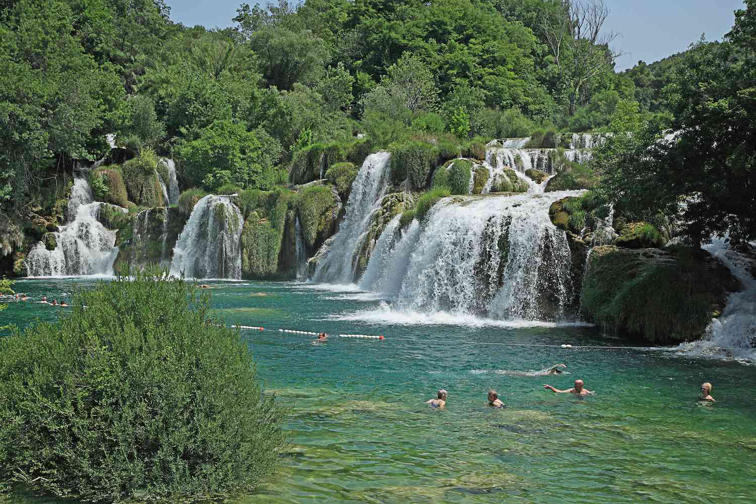 Los nadadores disfrutan de la piscina verde-azulada en la base de las cascadas de Skradinski Buk
