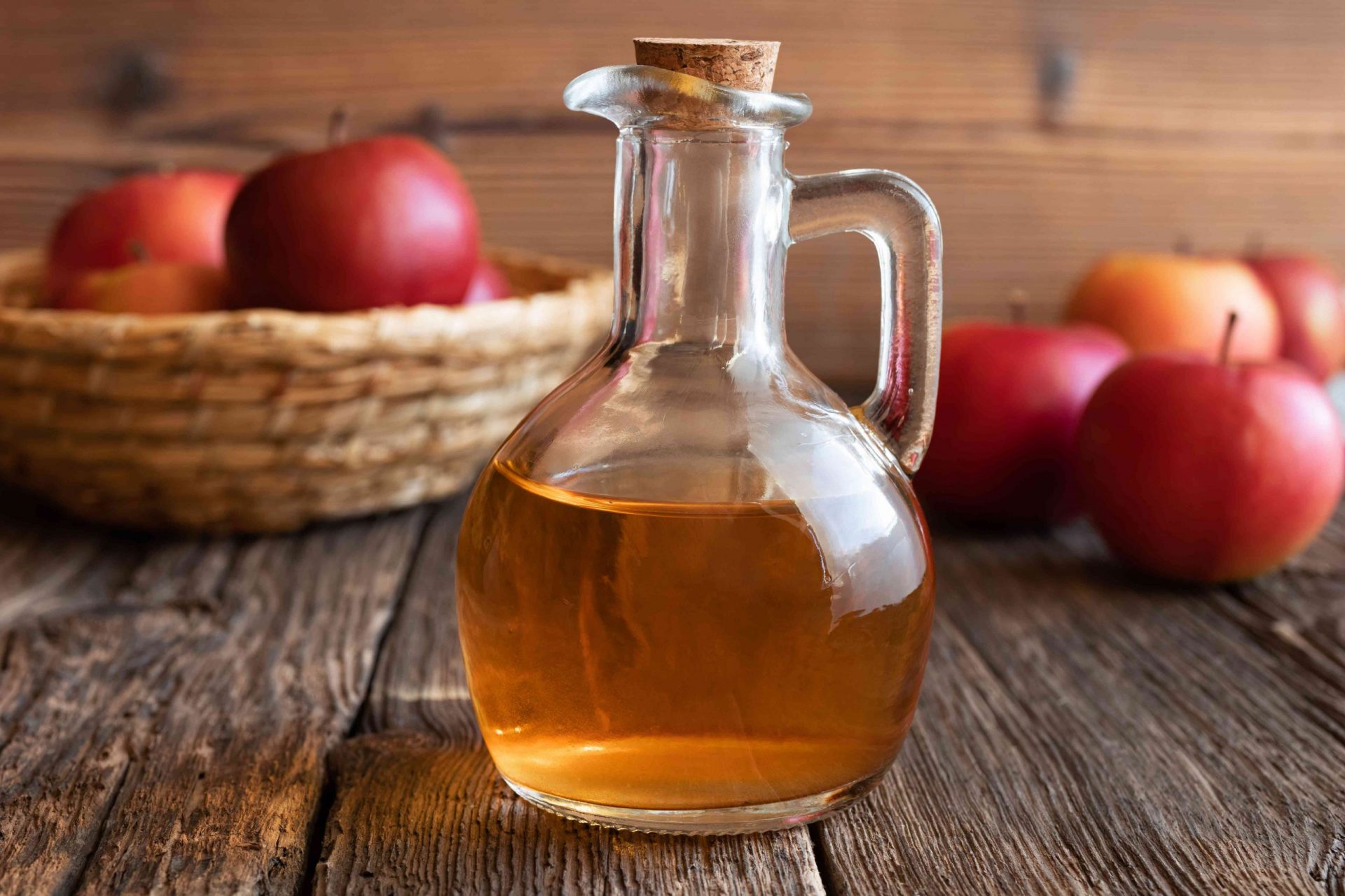 Una botella de vinagre de sidra de manzana con manzanas frescas